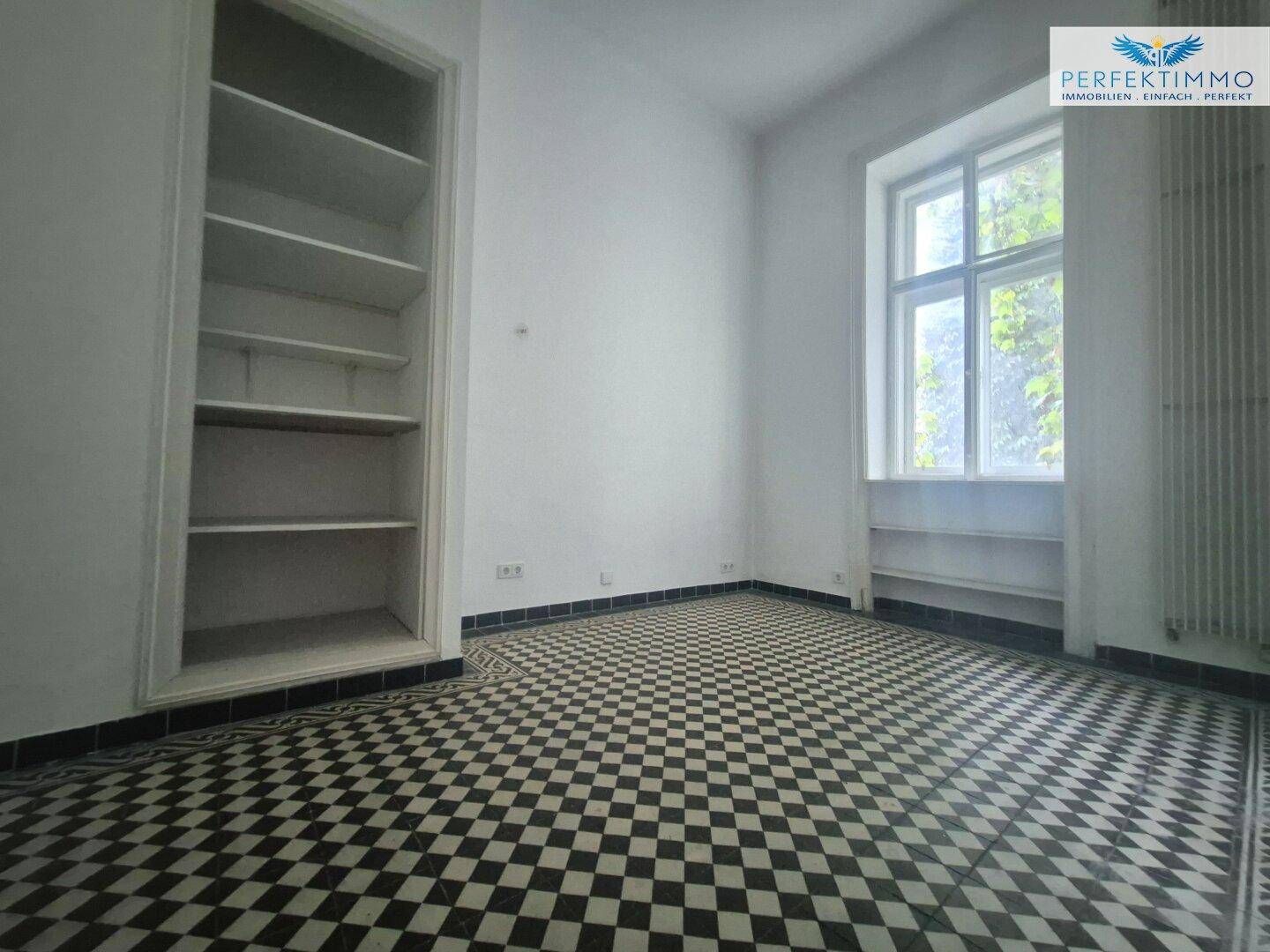 Zimmer mit auffälligem schwarz-weißem Schachbrettmuster-Fliesenboden und einem Einbauregal.