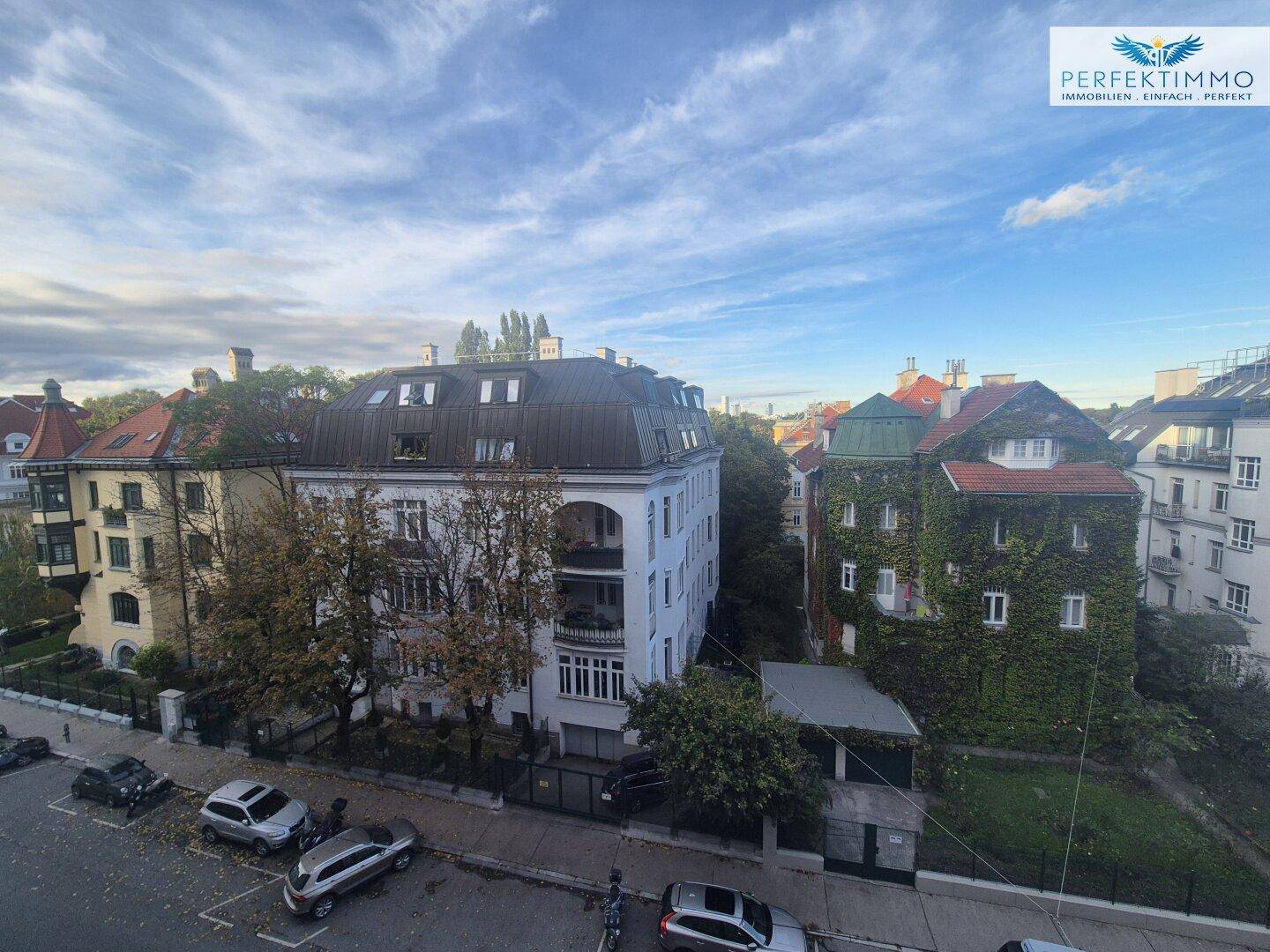Panoramablick über die Stadt mit verschiedenen Gebäuden und einer von Bäumen gesäumten Straße.