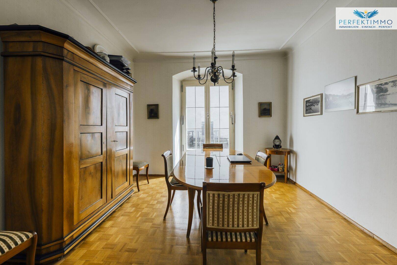 Geräumiger Essbereich mit Parkettboden, großem Holzschrank und hohen Fenstern.