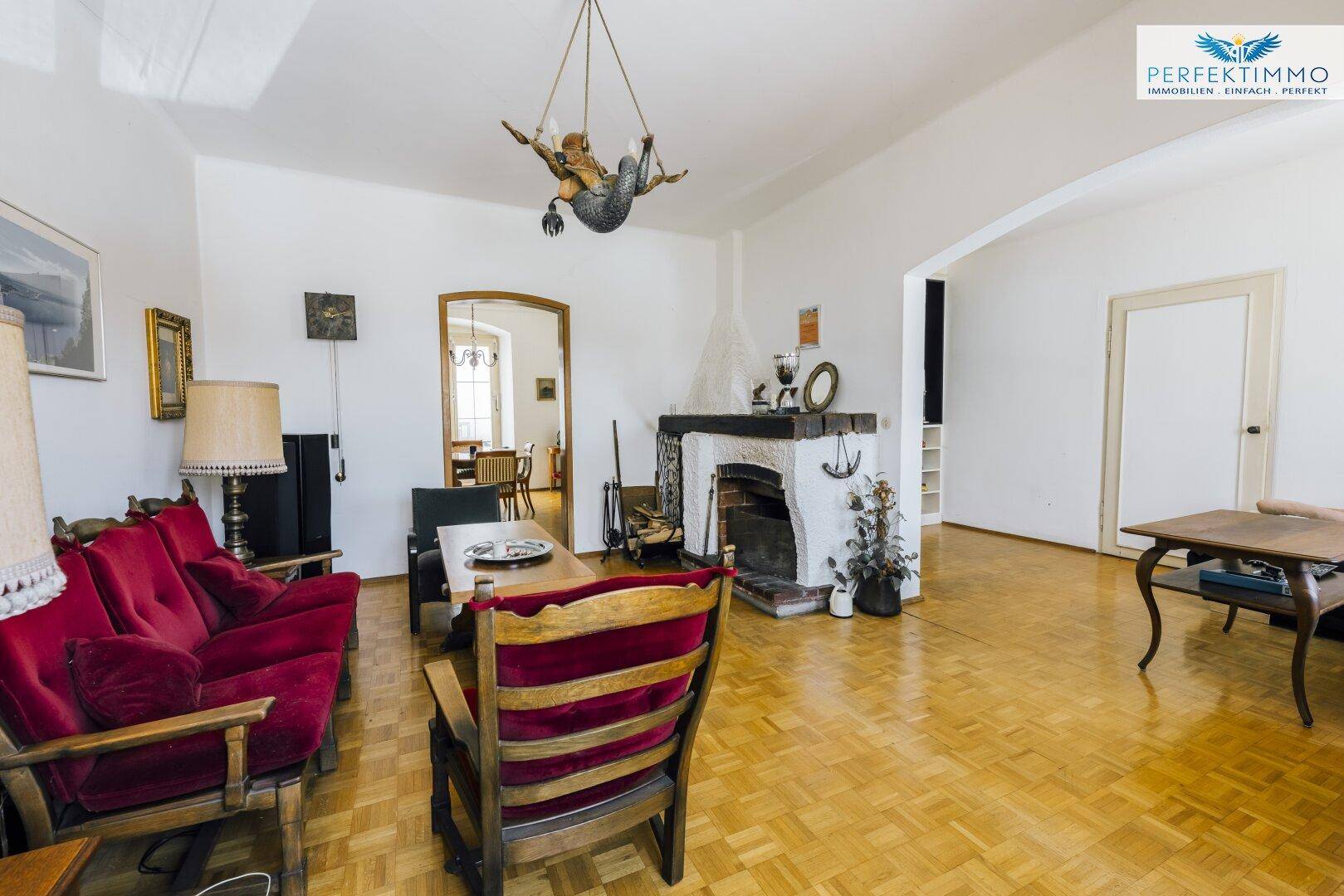 Gemütliches Wohnzimmer mit Parkettboden, Kamin und traditionellen Sitzmöbeln.