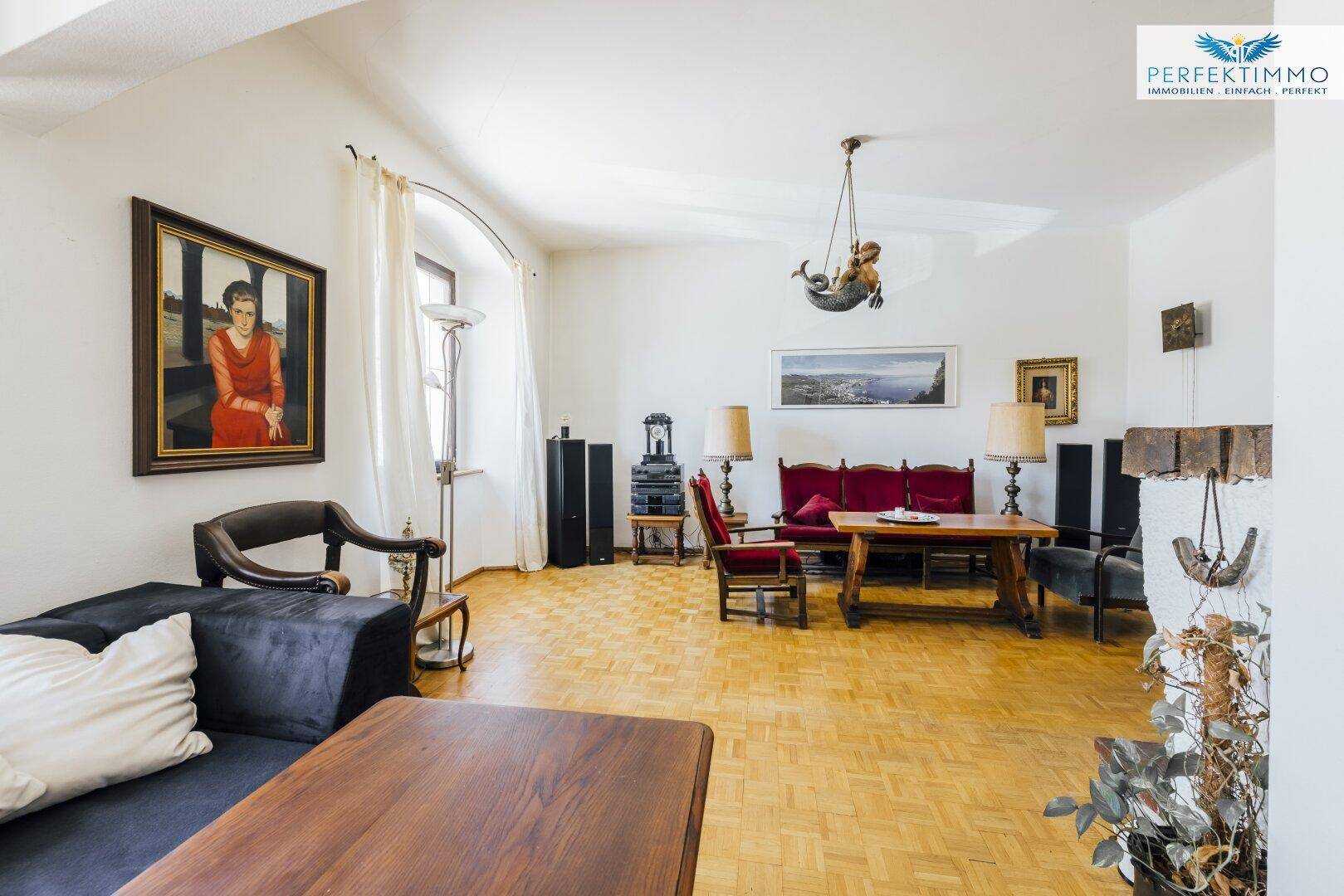 Geräumiges Wohnzimmer mit Parkettboden, Kamin und Blick auf die Stadt.