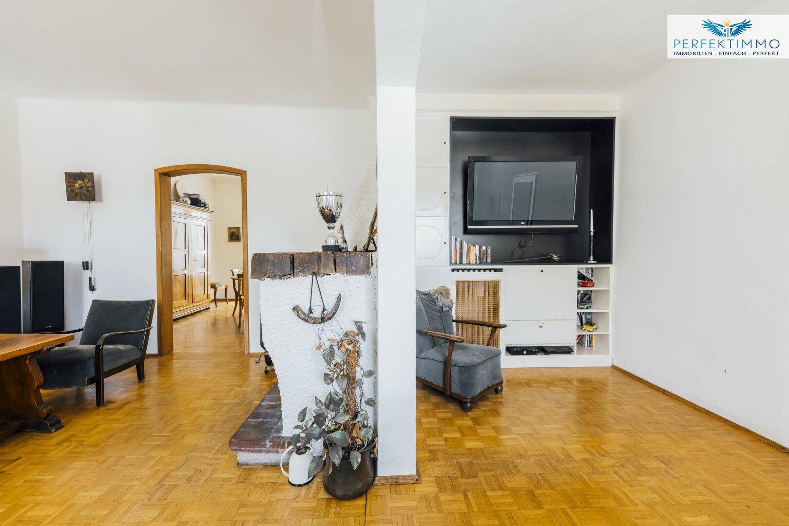Wohnzimmer mit Parkettboden, Kamin und integriertem TV-Bereich mit Regalen.