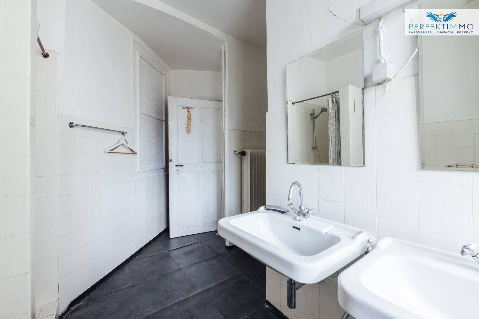 Badezimmer mit zwei Waschbecken, Spiegel und weiß gefliesten Wänden.
