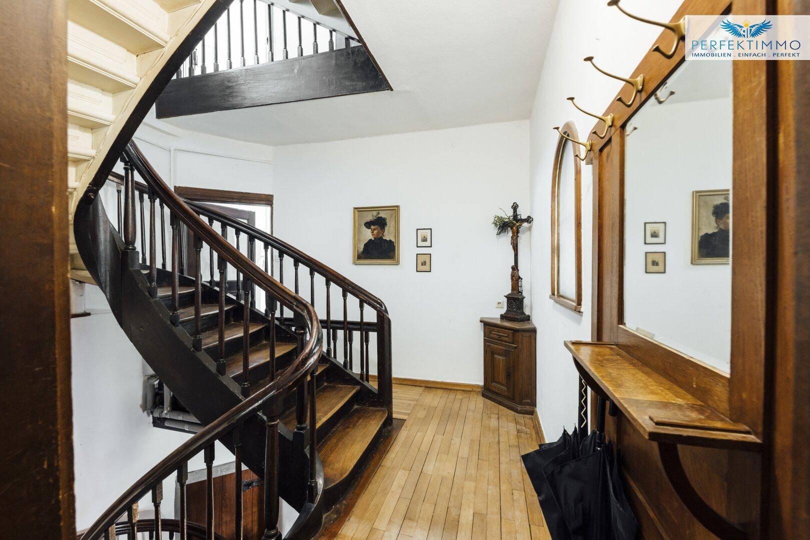 Historisches Treppenhaus mit Holzgeländer, Parkettboden und traditioneller Dekoration.