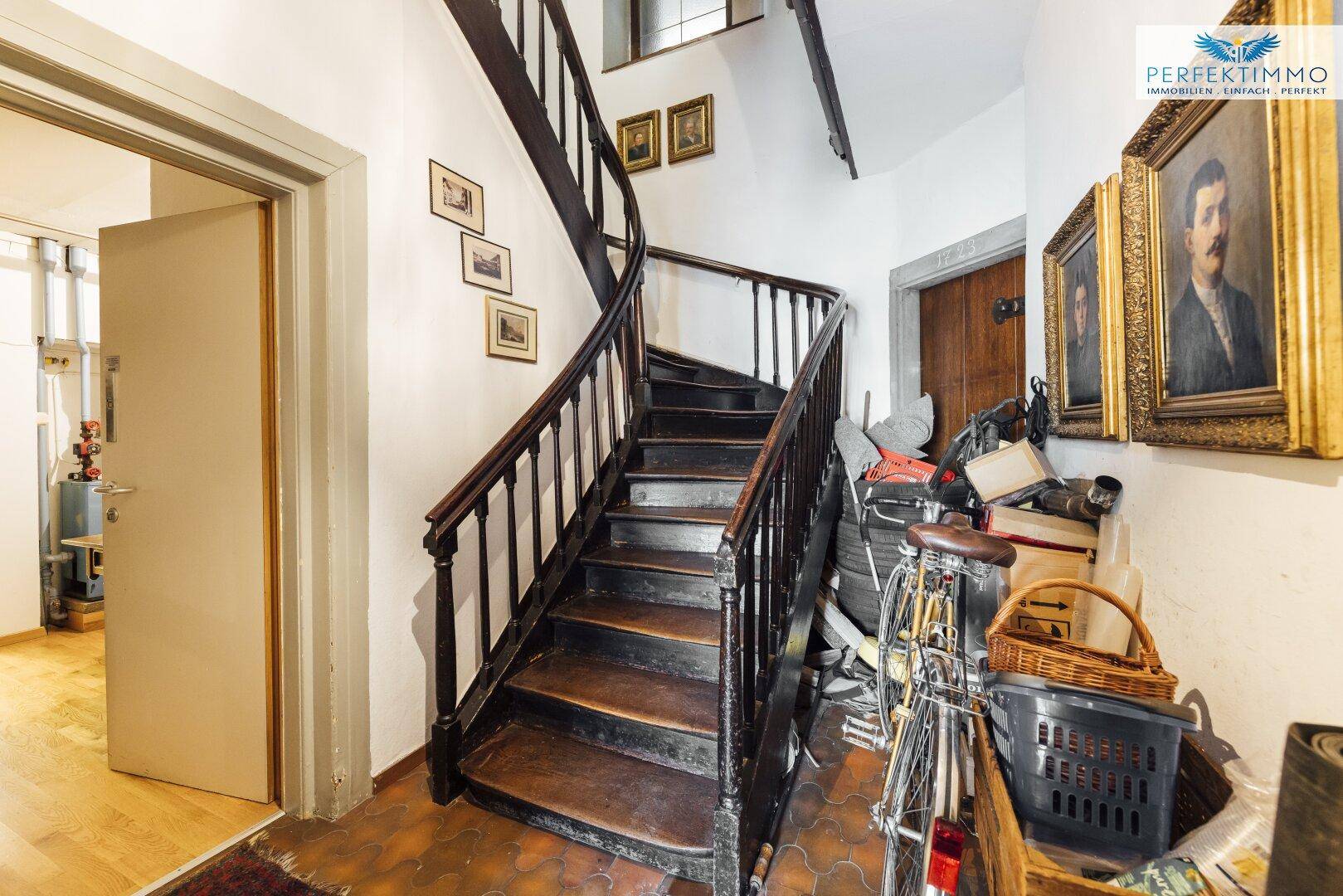 Treppenhaus mit Holzstufen, Fliesenboden und Stauraum unter der Treppe.