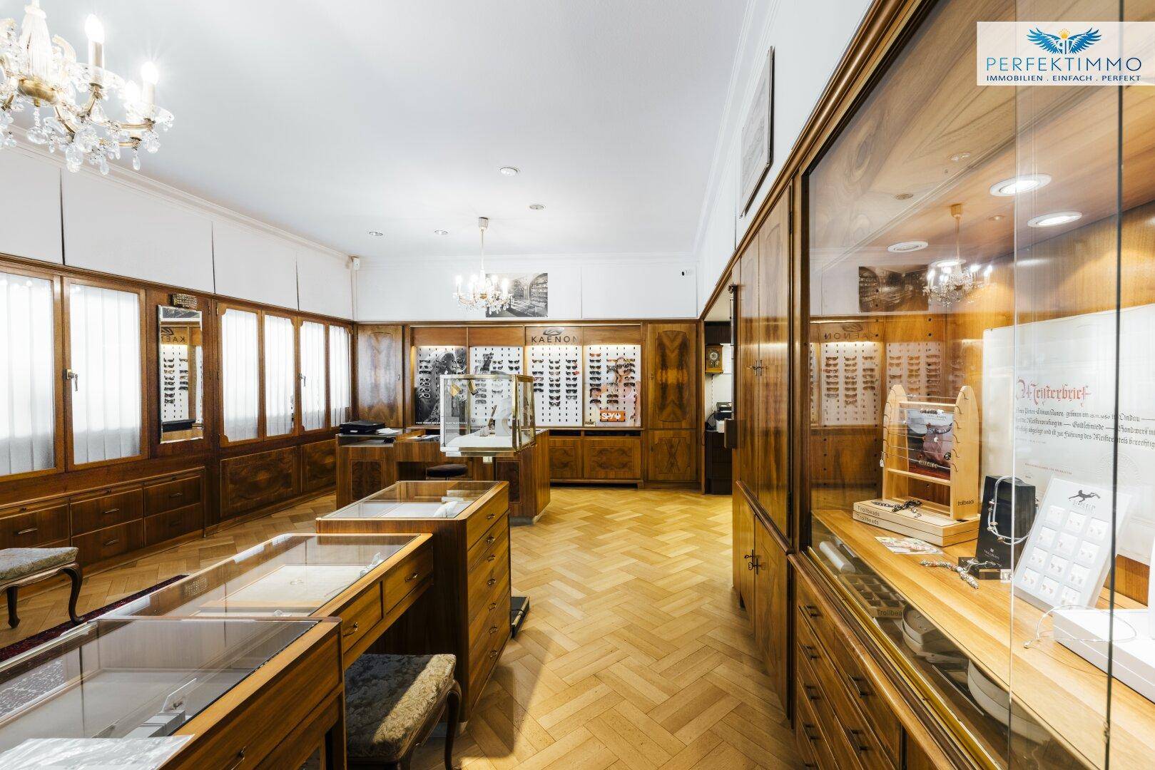Verkaufsraum mit Holzvitrinen, Parkettboden und Auslagen für Brillen und Schmuck.