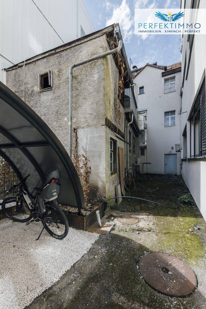 Schmaler Hinterhof mit Fahrradunterstand und alter Bausubstanz.