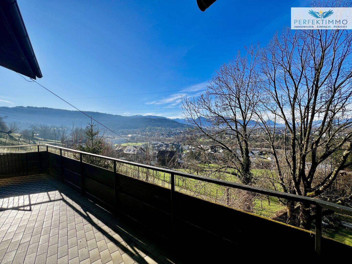 Geräumige geflieste Terrasse mit Metallgeländer und Panoramablick auf die Stadt und die Berge.
