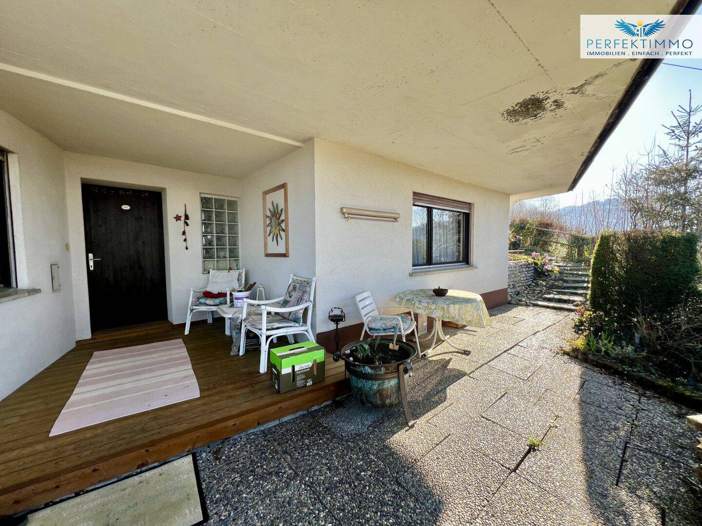 Überdachte Terrasse mit Sitzgelegenheiten und Zugang zum Garten, ideal für Entspannung im Freien.