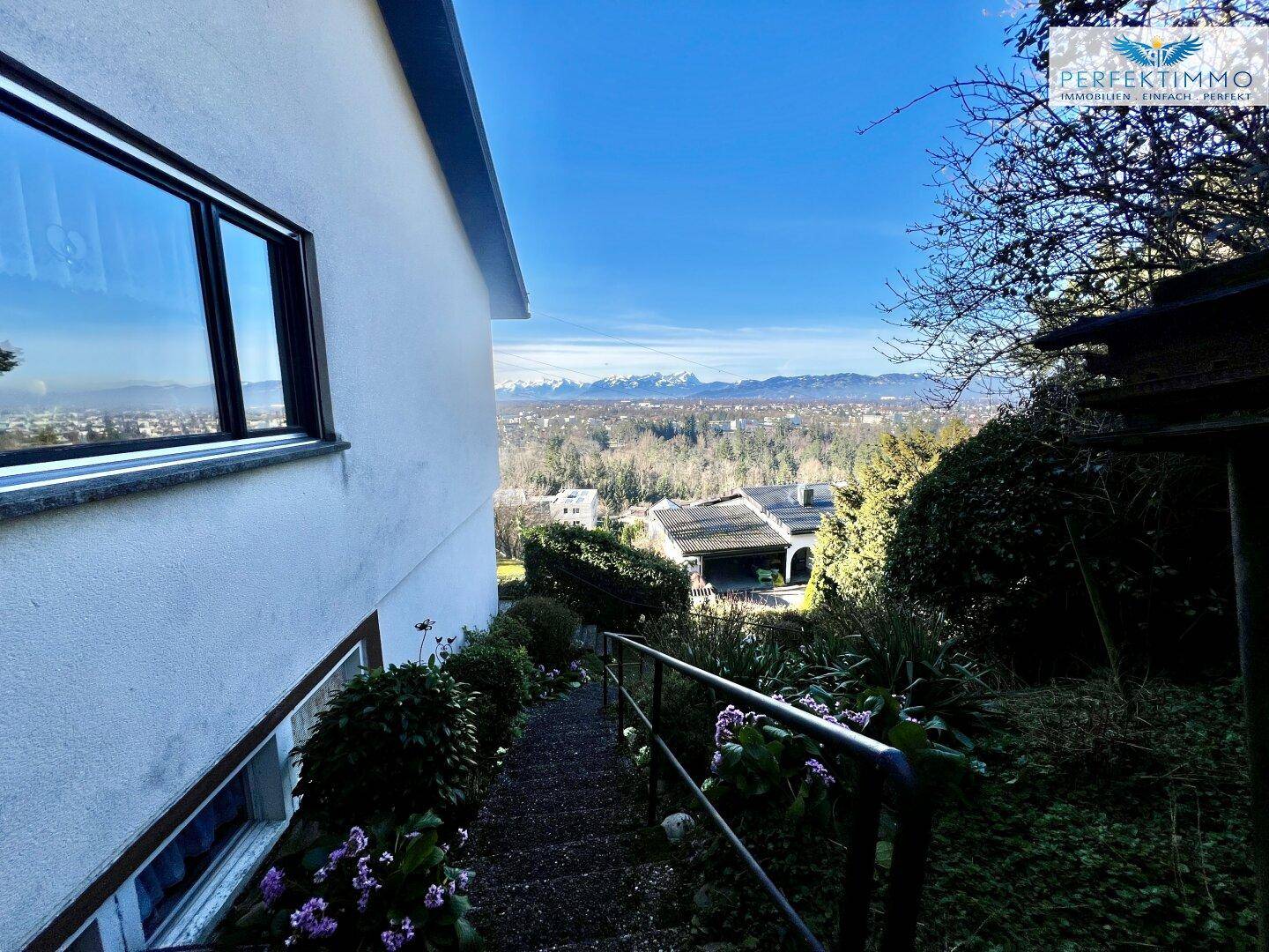 Außentreppe am Haus mit weitem Blick über die bewaldete Landschaft und die Berge.