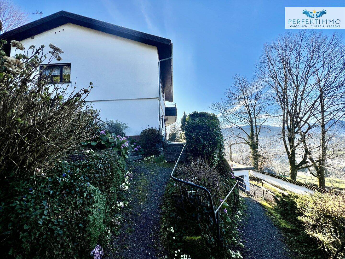 Auffahrt zum Haus mit Blick auf die umliegende grüne Landschaft und die Berge.