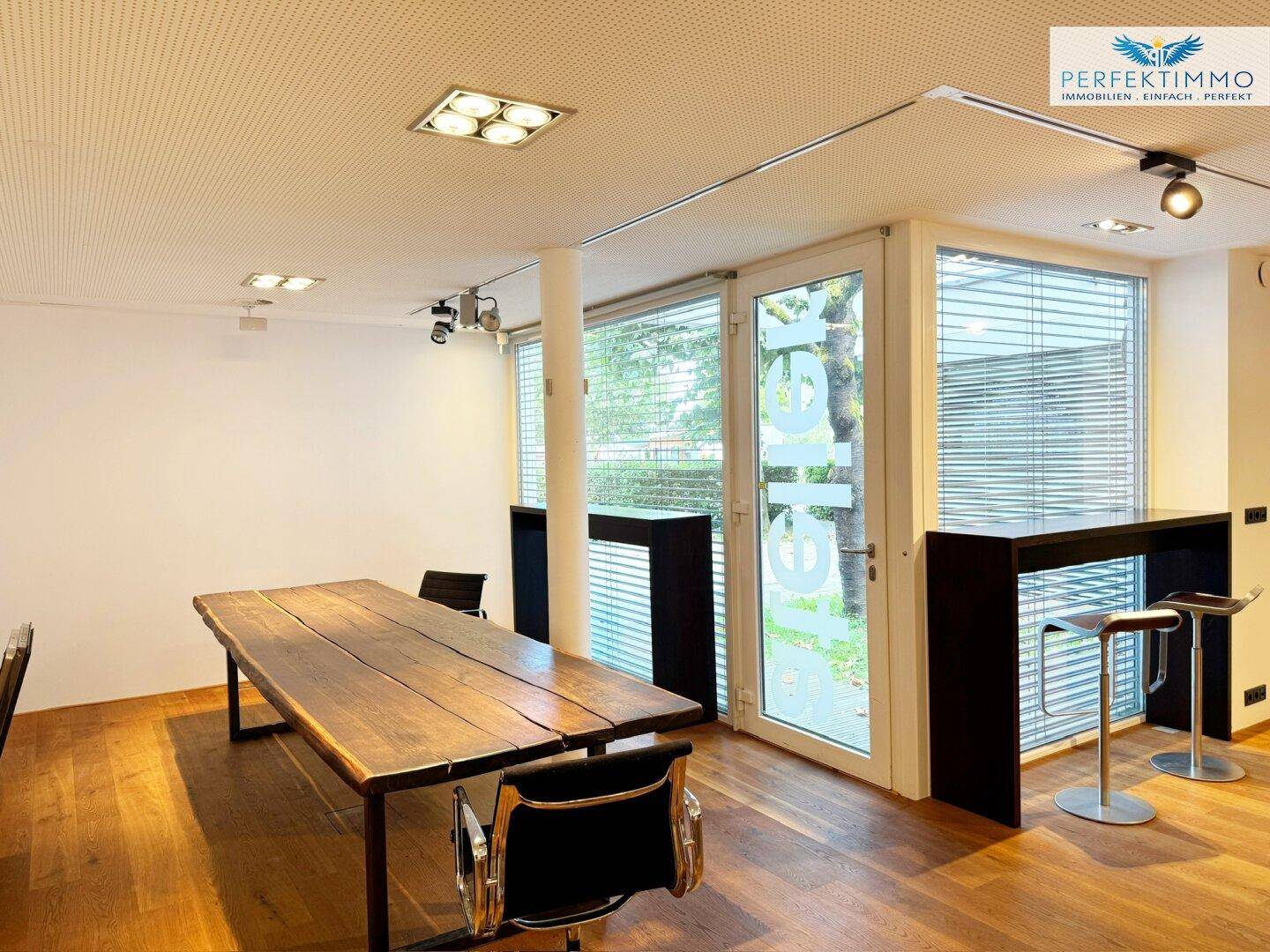 Heller Gewerberaum mit Holzboden, großen Fenstern und einer modernen Bar-Theke.