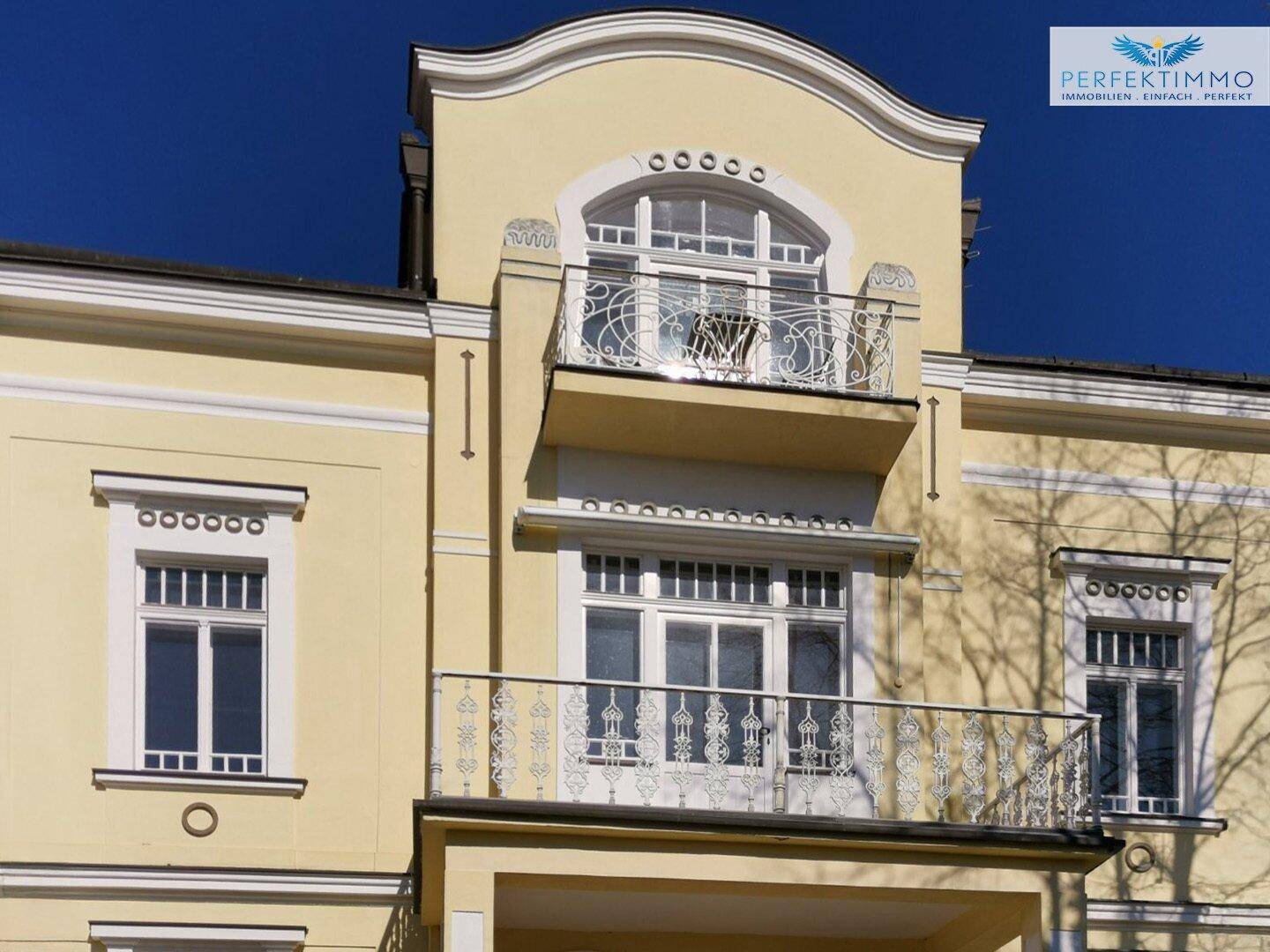 Nahaufnahme der oberen Balkone mit filigranen Geländern und dekorativen Fassadendetails der Villa.