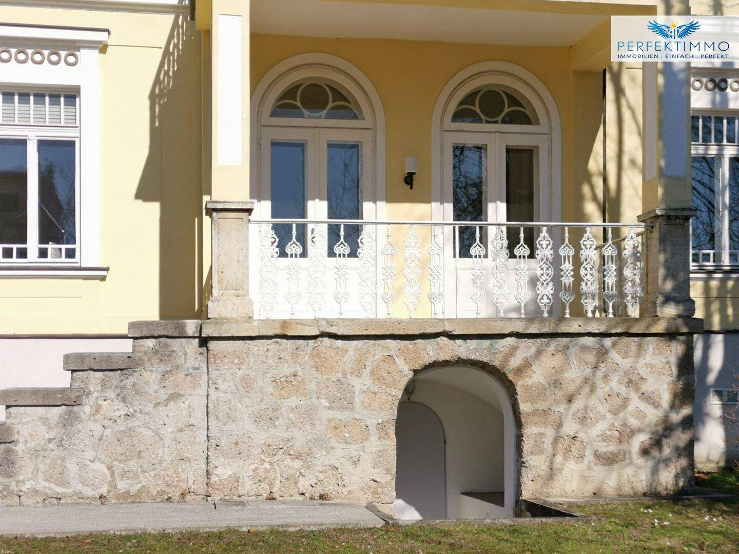Haupteingang der Villa mit Steintreppe, Balkon und Zugang zum Kellergeschoss.