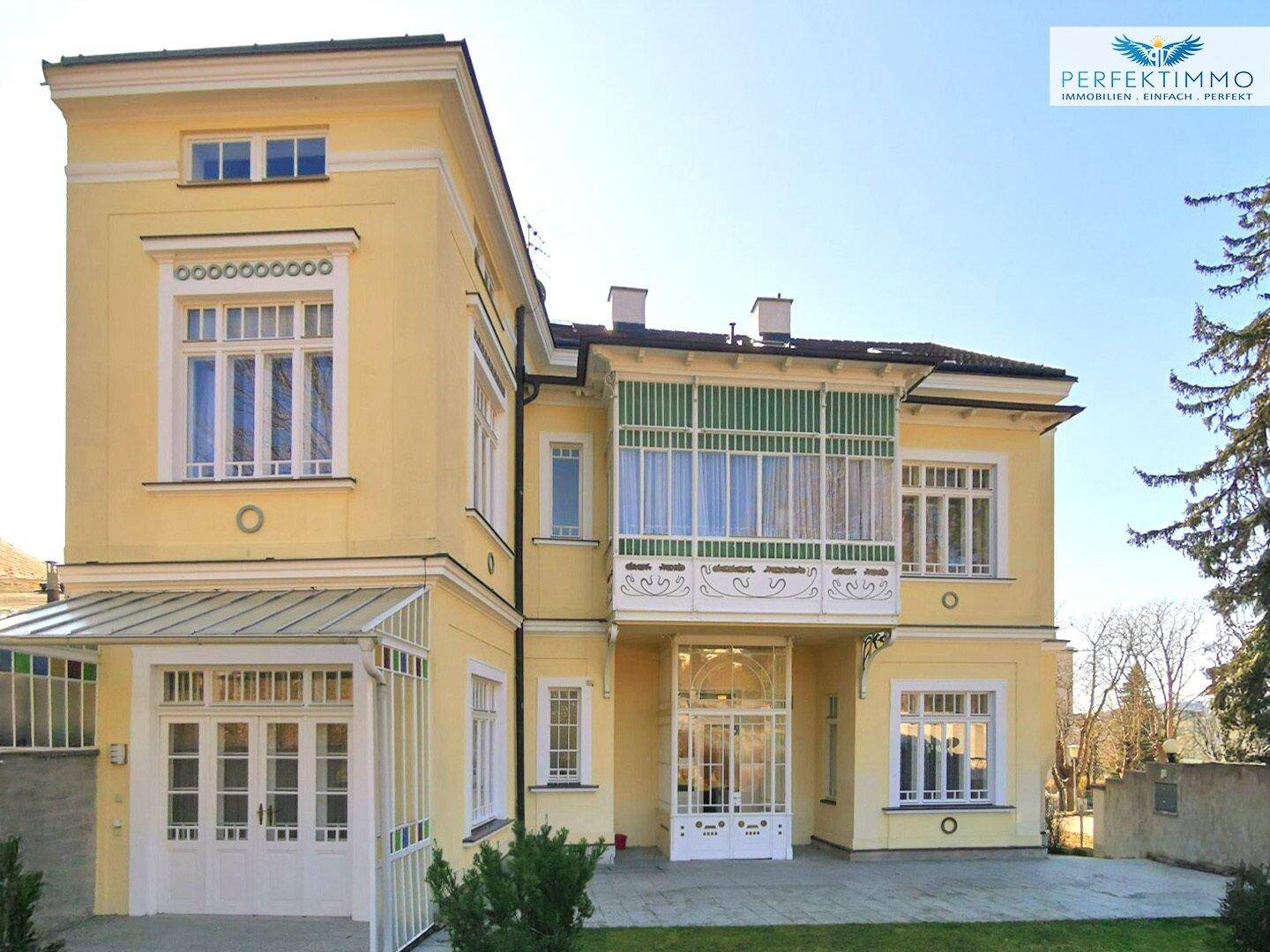 Ansicht der Villa von vorne mit gepflegtem Vorgarten und dekorativen Elementen.
