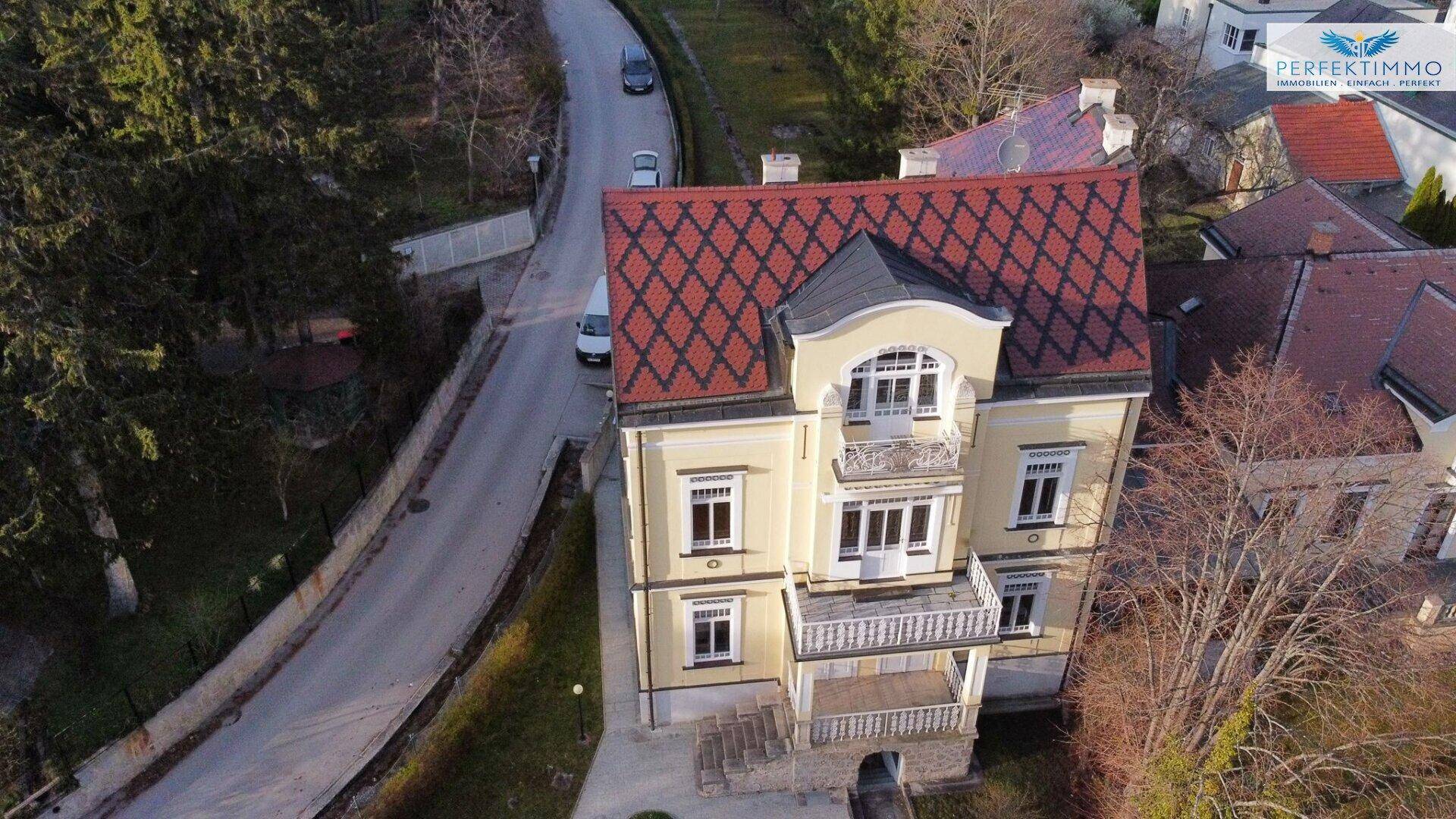 Luftaufnahme der Villa mit rotem Ziegeldach und der angrenzenden Straße.