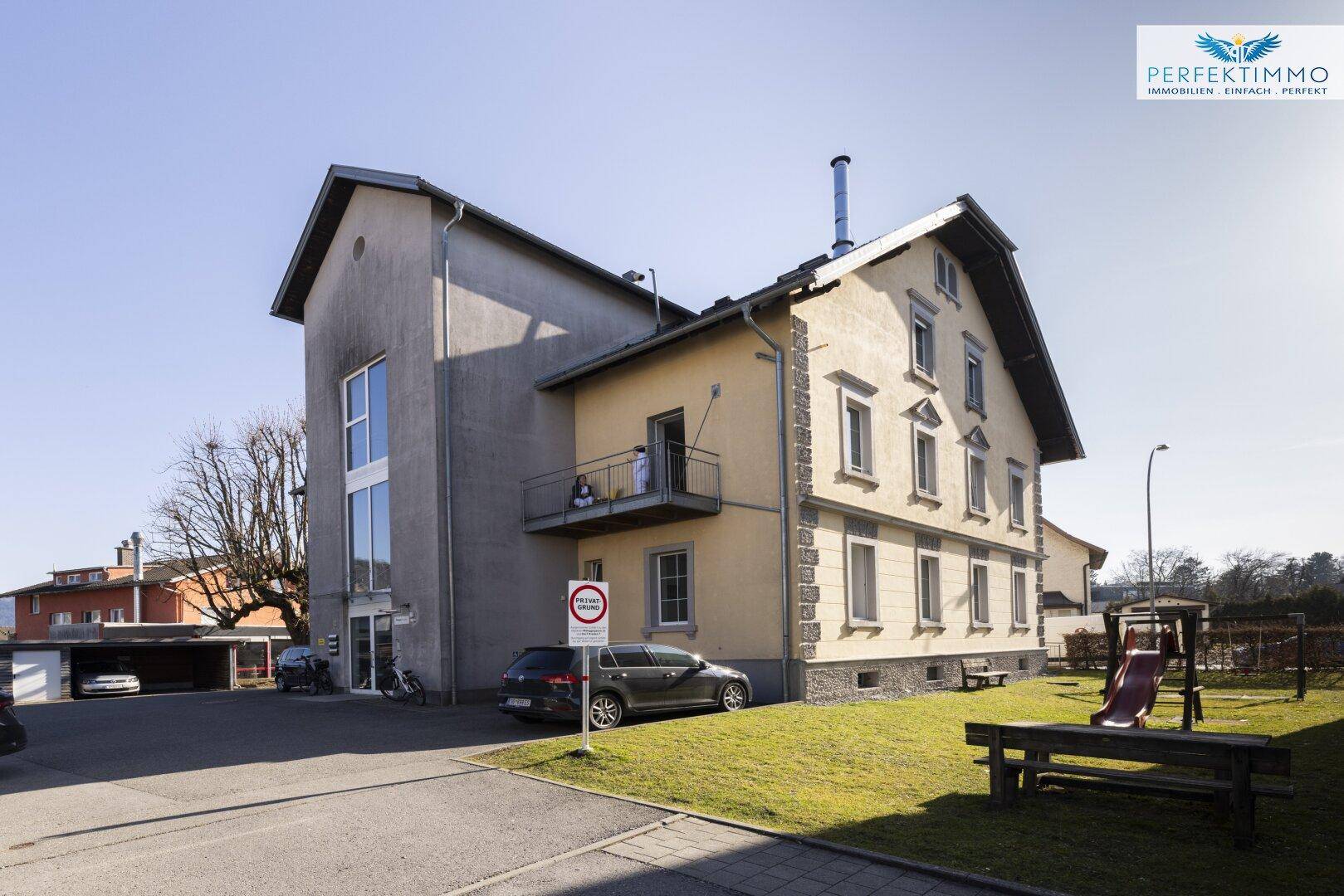 Seitenansicht des Gebäudes mit einem kleinen Spielplatz und Balkon.