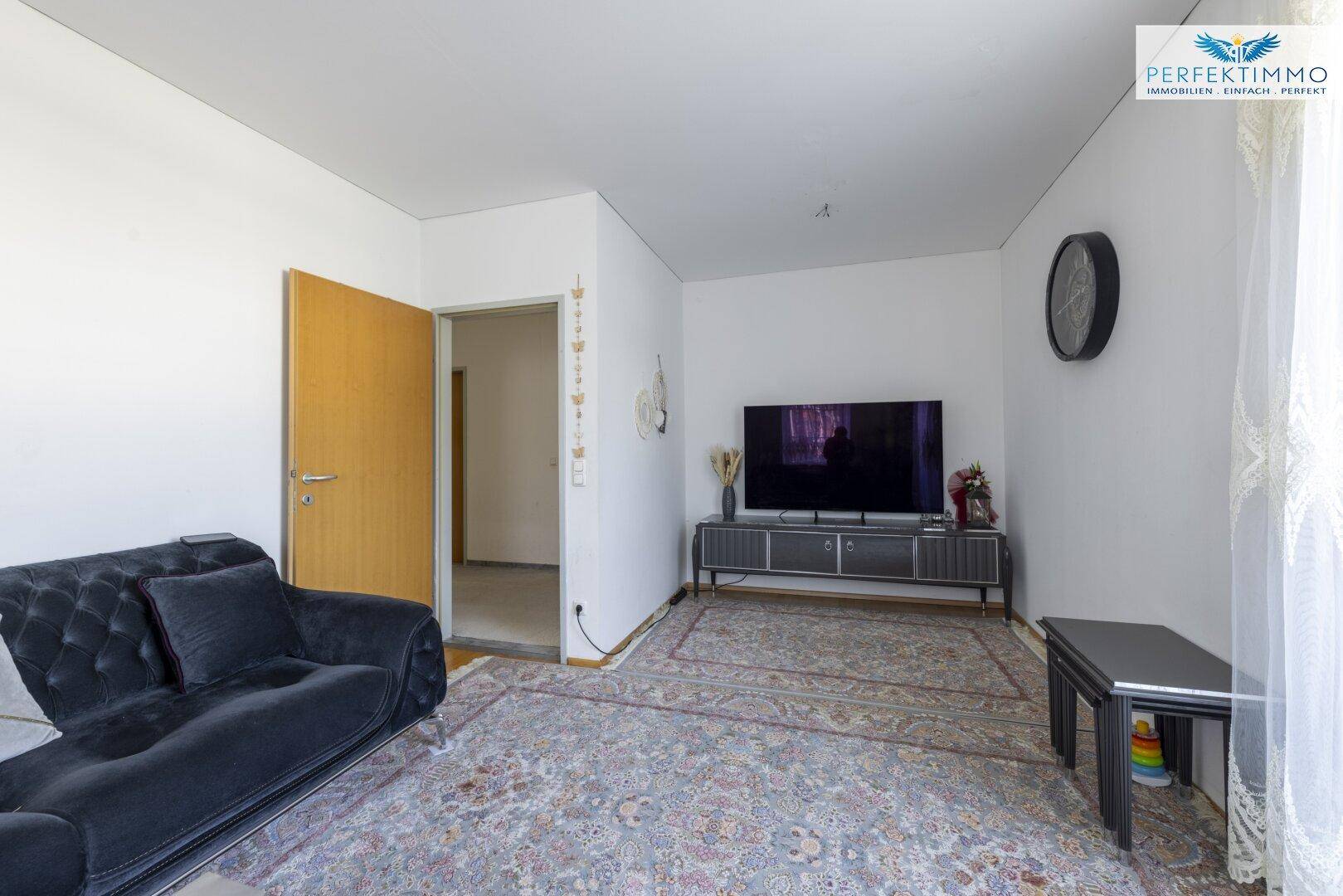 Wohnzimmer mit Teppichboden, Fernseher und einem Sofa, das zum Entspannen einlädt.