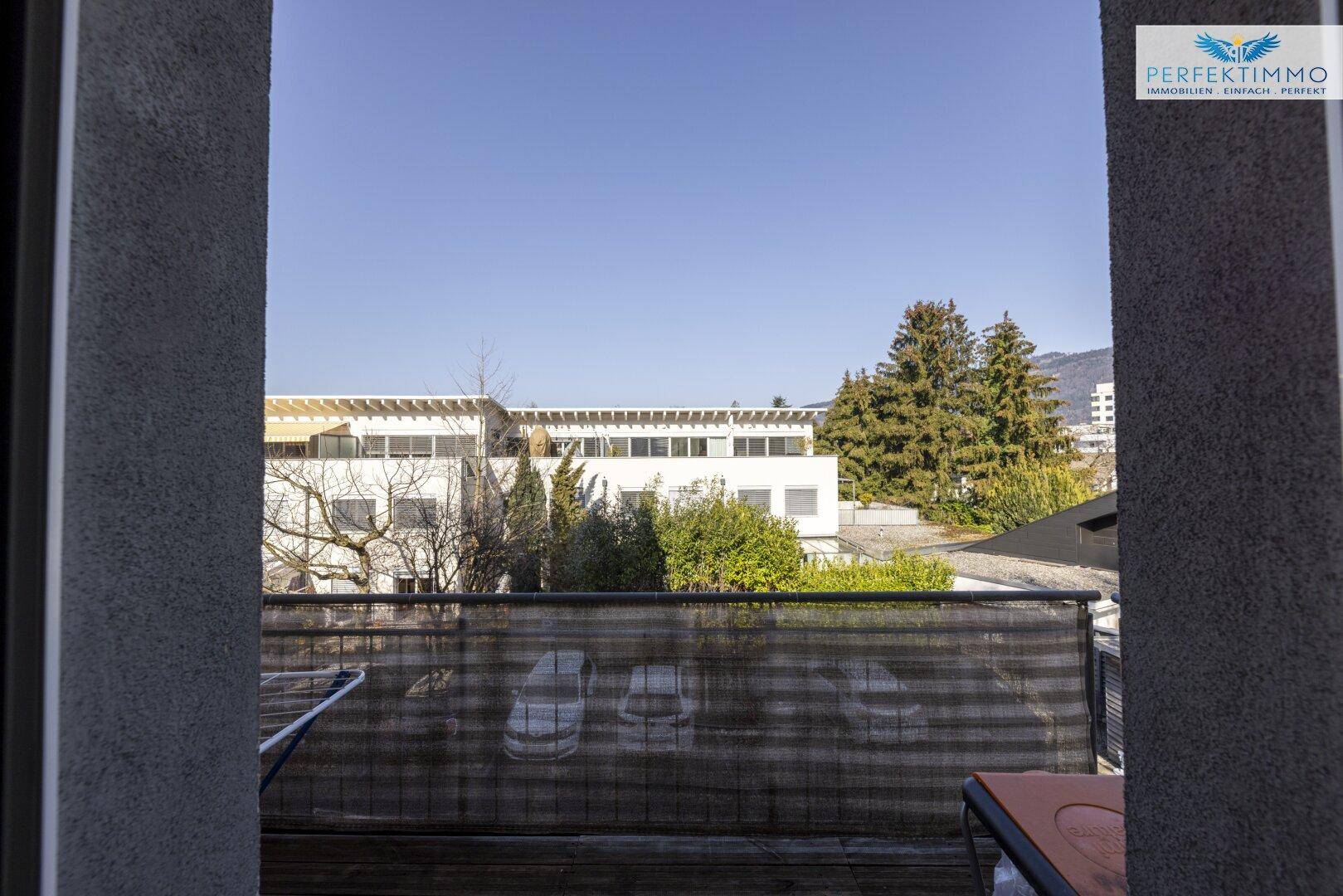 Blick vom Balkon auf die Umgebung mit Bäumen und anderen Gebäuden.
