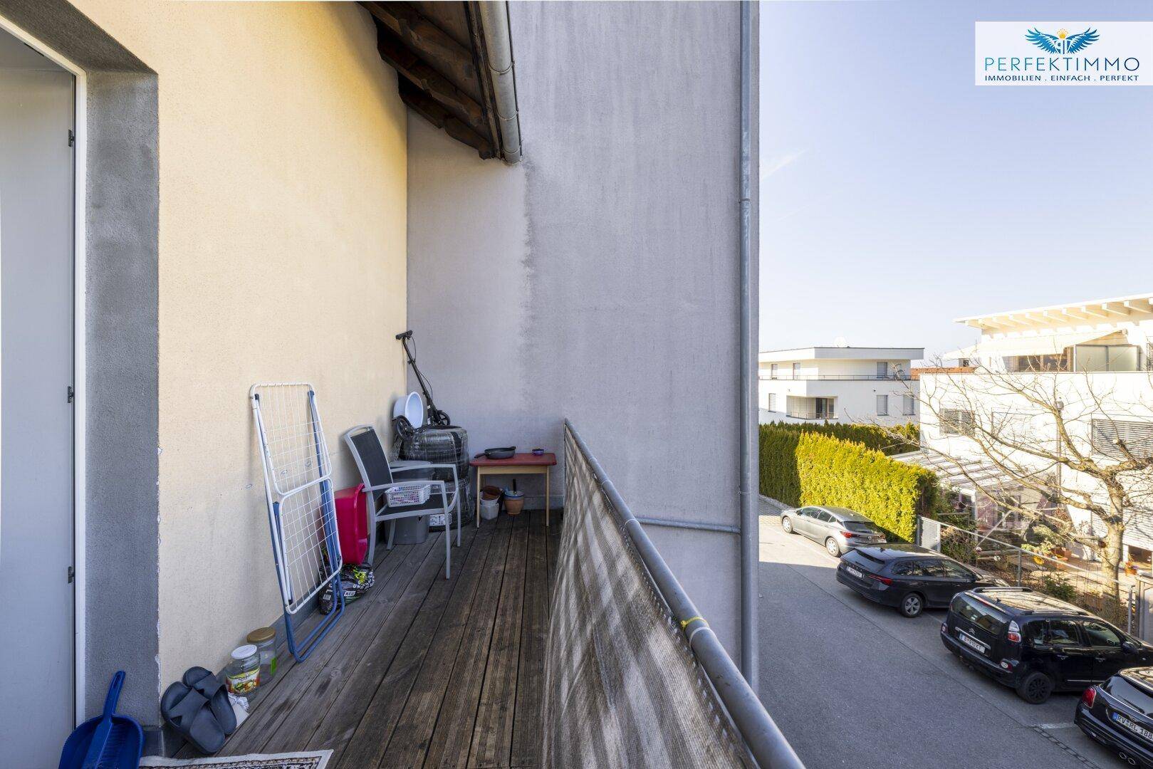 Kleiner Balkon mit Holzboden und einfacher Möblierung, ideal für sonnige Stunden.