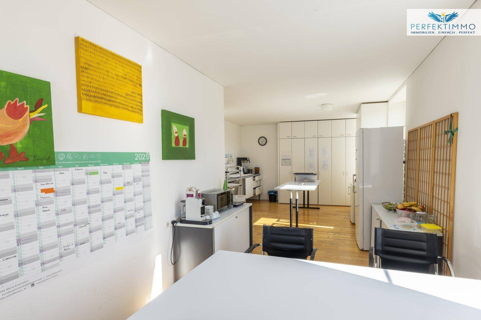 Weitläufige Küche mit viel Stauraum, Holzboden und bunten Bildern an den Wänden.