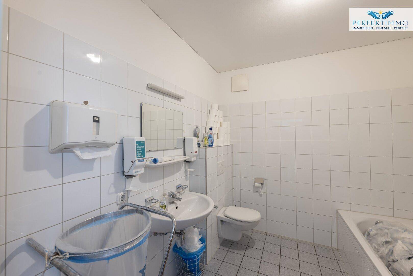 Gefliestes Badezimmer mit Waschbecken, Toilette und Badewanne, funktional und sauber.