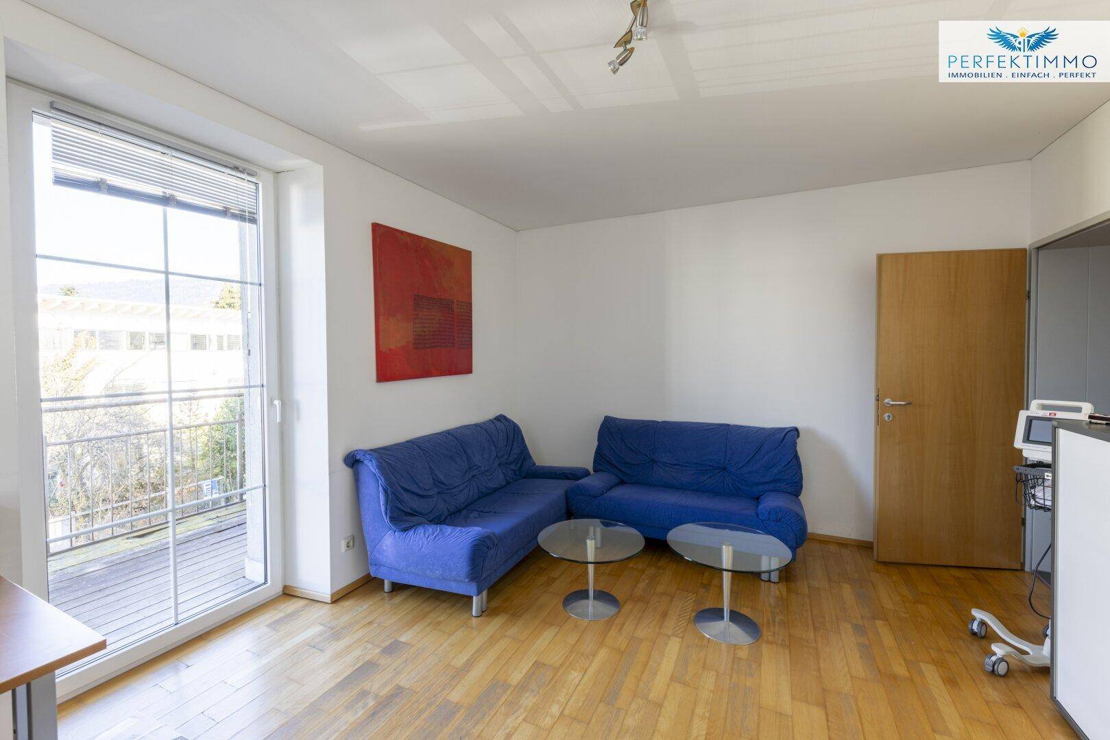 Geräumiges Büro mit Holzboden, bequemen Sofas und großen Fenstern mit Blick nach draußen.