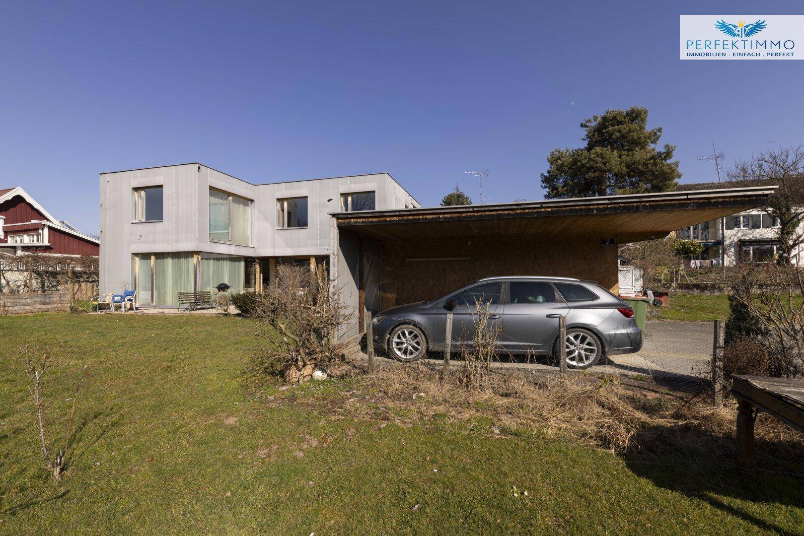 Seitenansicht des Hauses mit Carport und großem Gartenbereich.