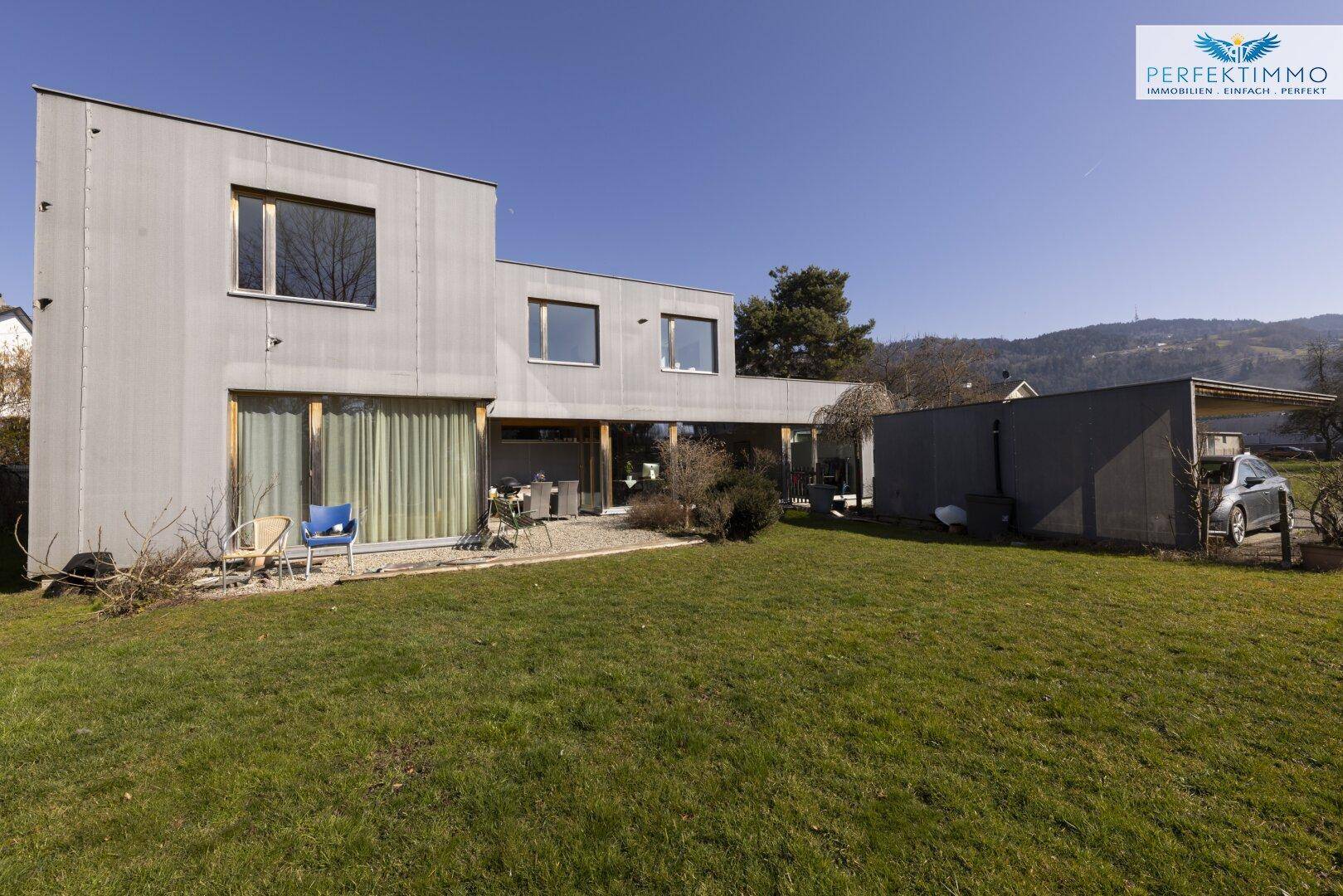 Modernes Einfamilienhaus mit weitläufigem Garten und Carport.