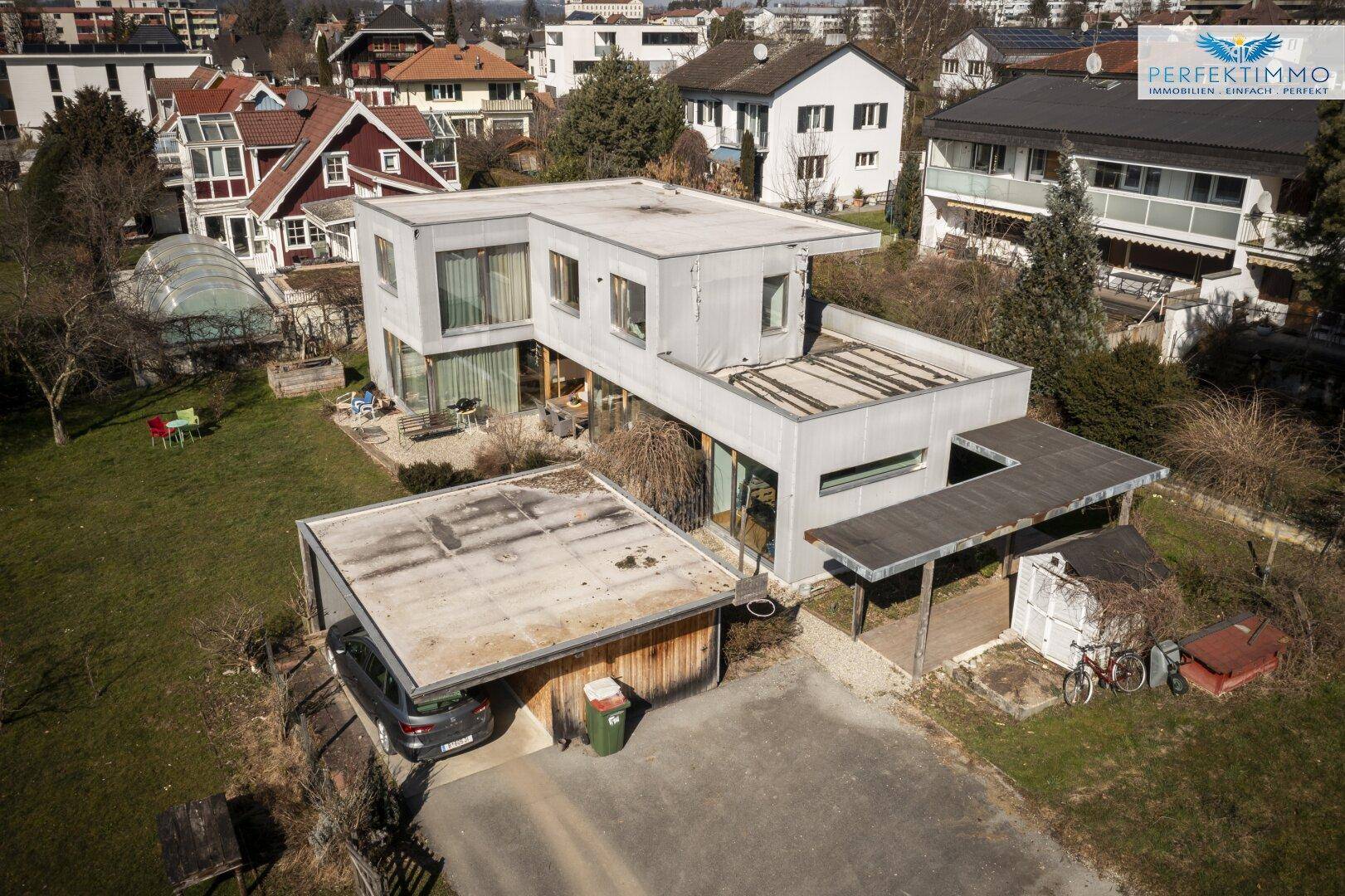 Luftaufnahme des modernen Hauses mit Flachdach und umliegender Bebauung.