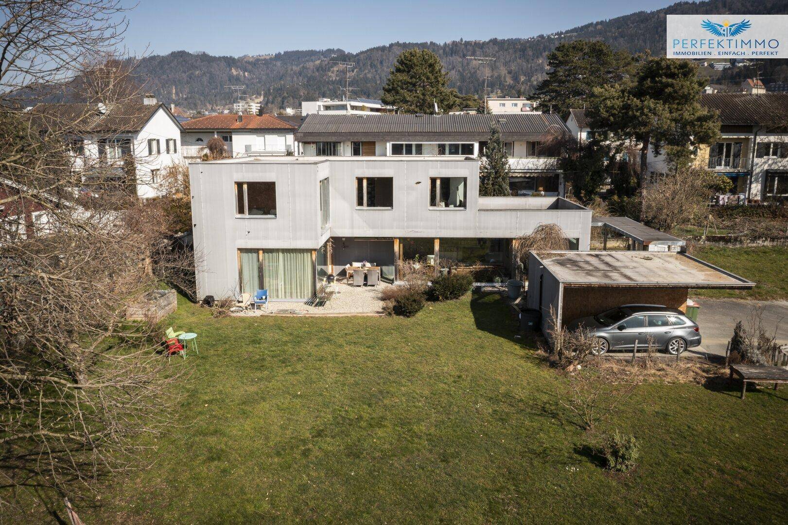 Luftaufnahme des modernen Hauses mit Garten und Carport in Wohngegend.