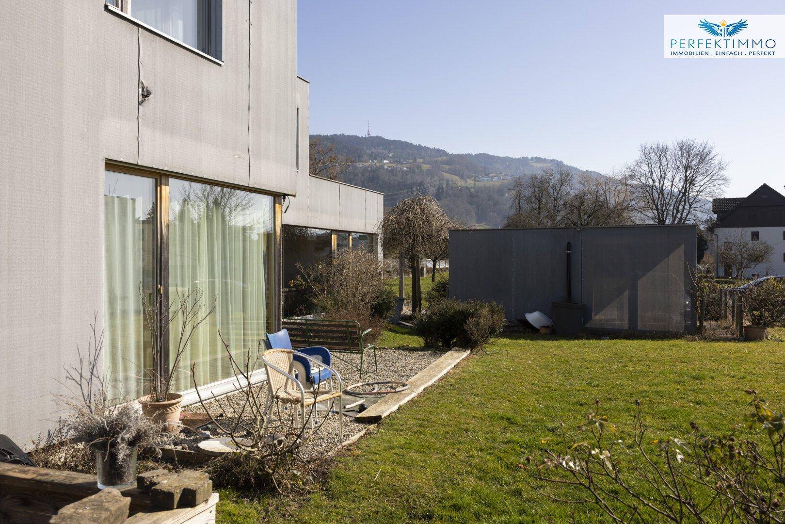 Gartenbereich mit Sitzgelegenheiten und Blick auf die umliegende Landschaft.