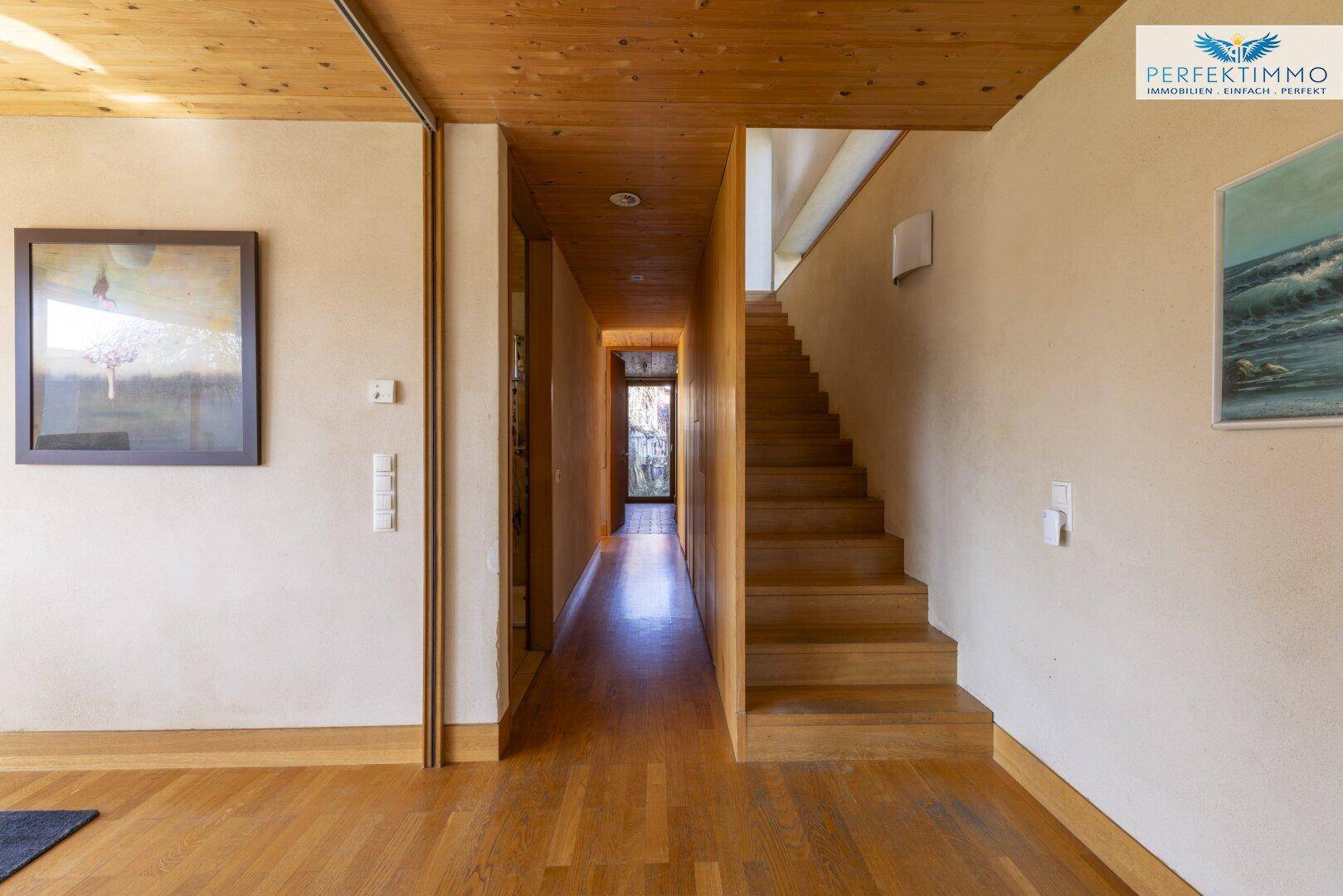 Heller Flur mit Holztreppe, Holzboden und Zugang zu weiteren Räumen.