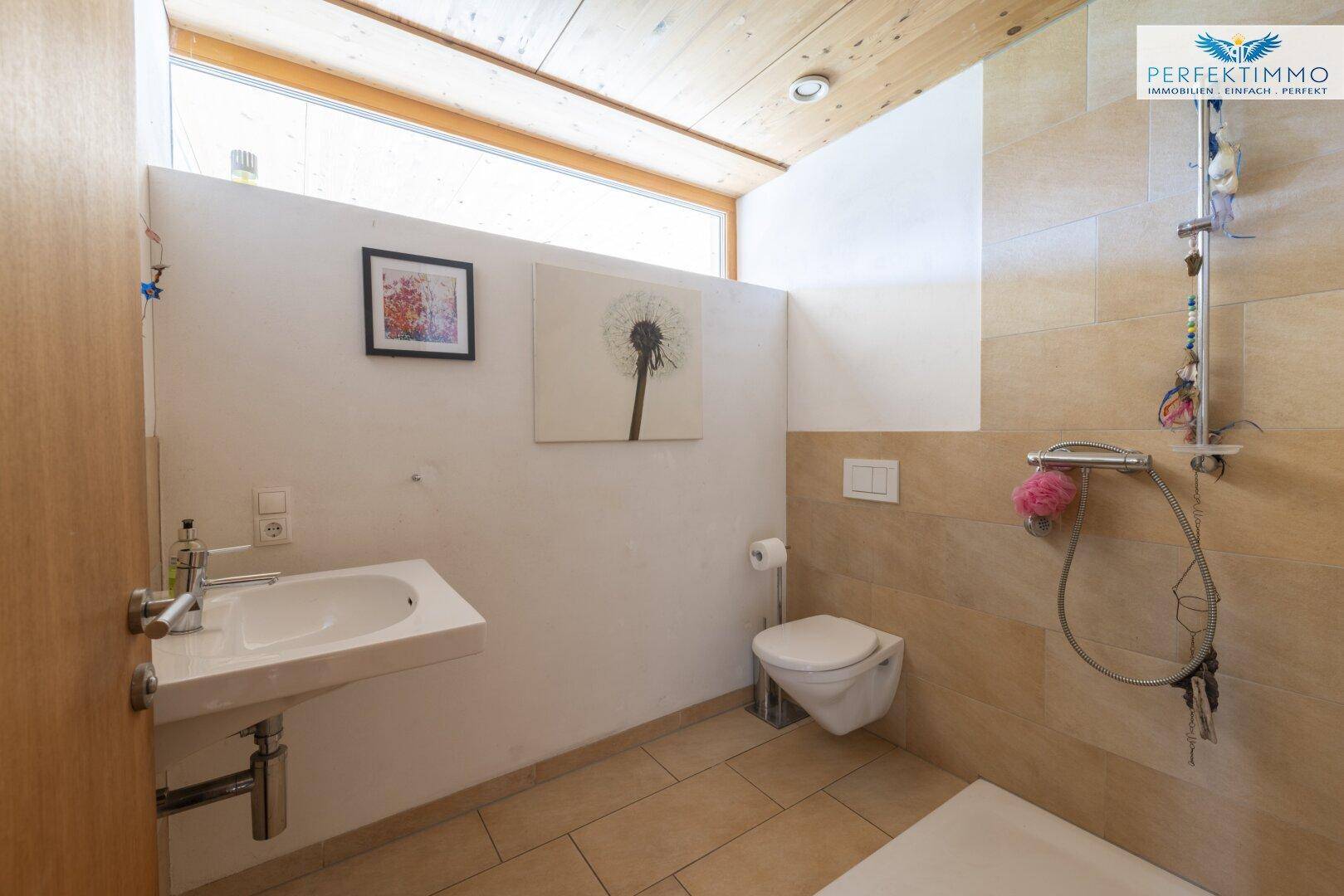 Modernes Badezimmer mit Dusche, wandhängendem WC und Fenster.