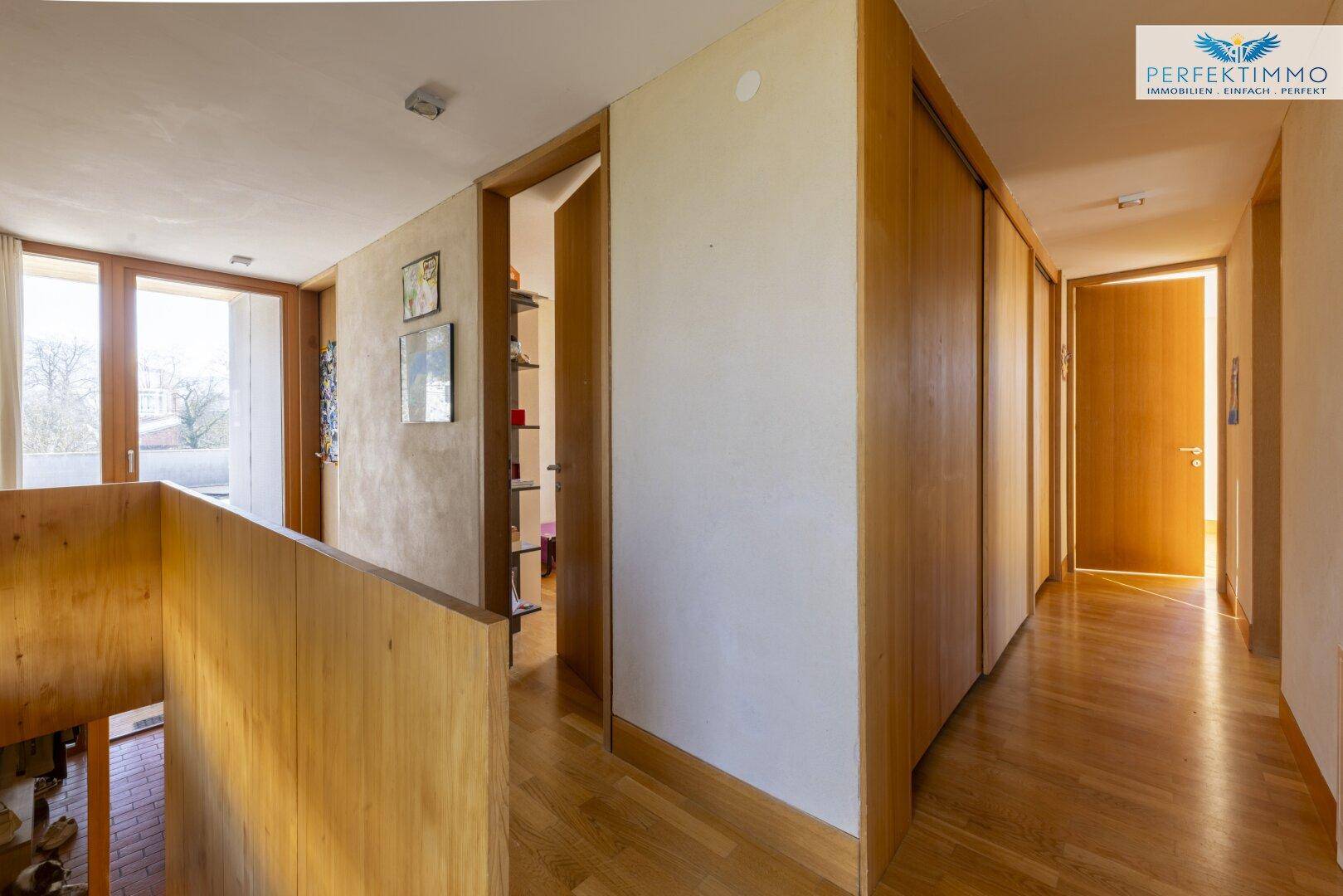 Heller Flur im Obergeschoss mit Einbauschränken und Holzboden.