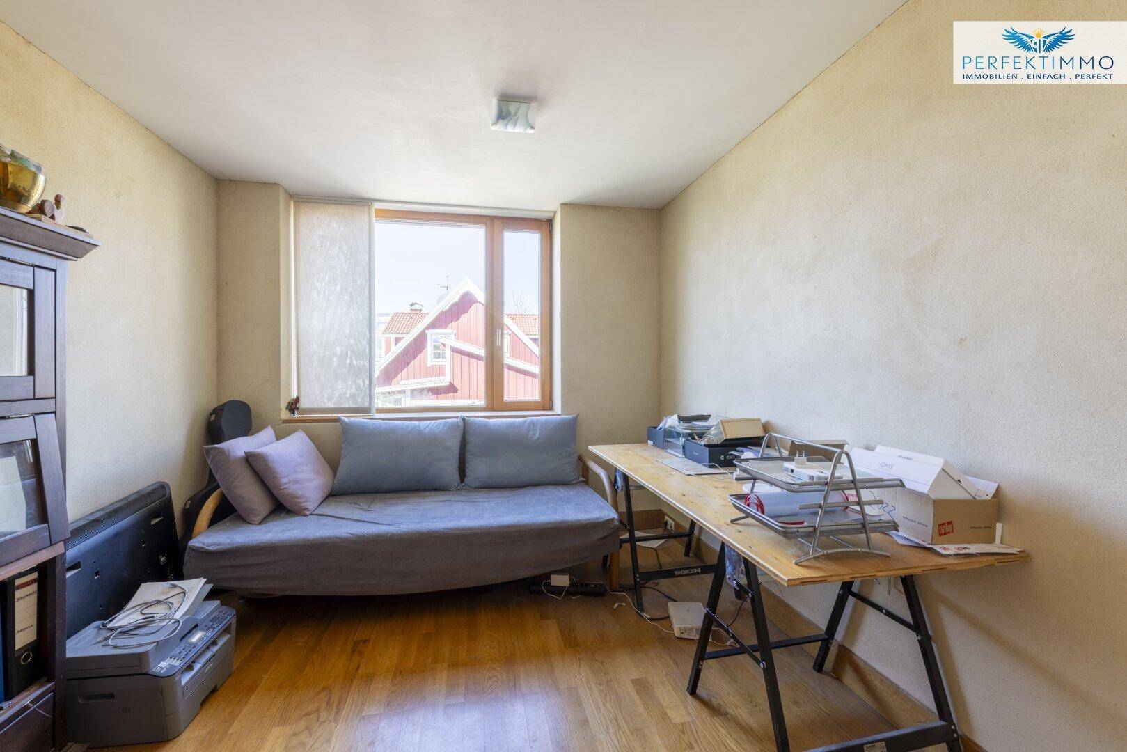 Arbeitszimmer mit Schreibtisch, Sofa und Fenster mit Blick auf die Umgebung.
