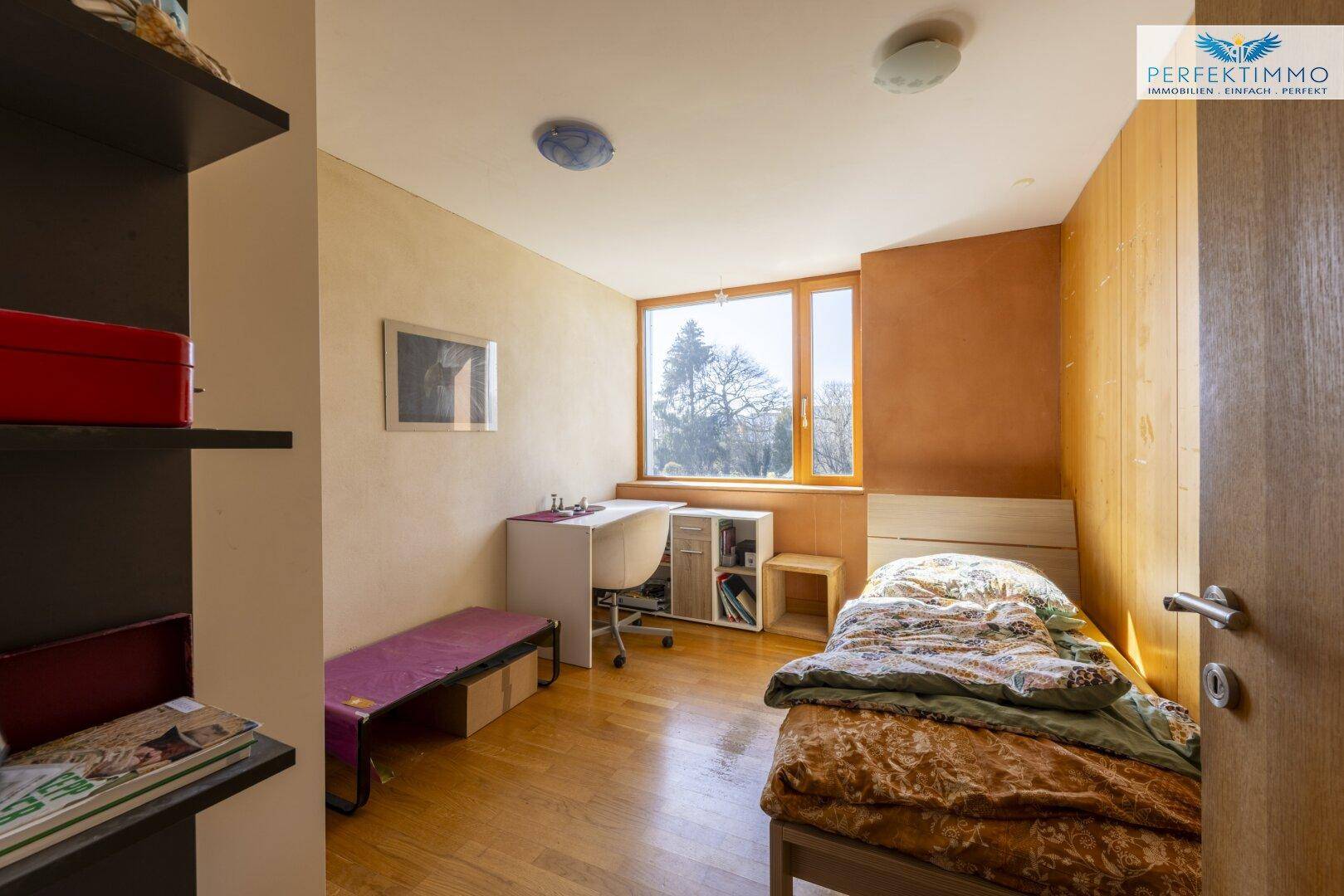 Kinderzimmer oder Gästezimmer mit Einzelbett, Schreibtisch und Holzboden.
