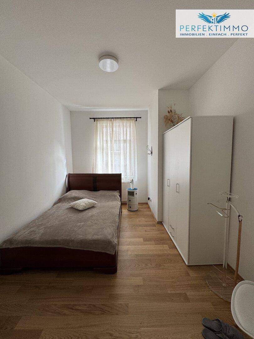 Schlafzimmer mit Einzelbett, weißem Kleiderschrank und hellem Holzboden.