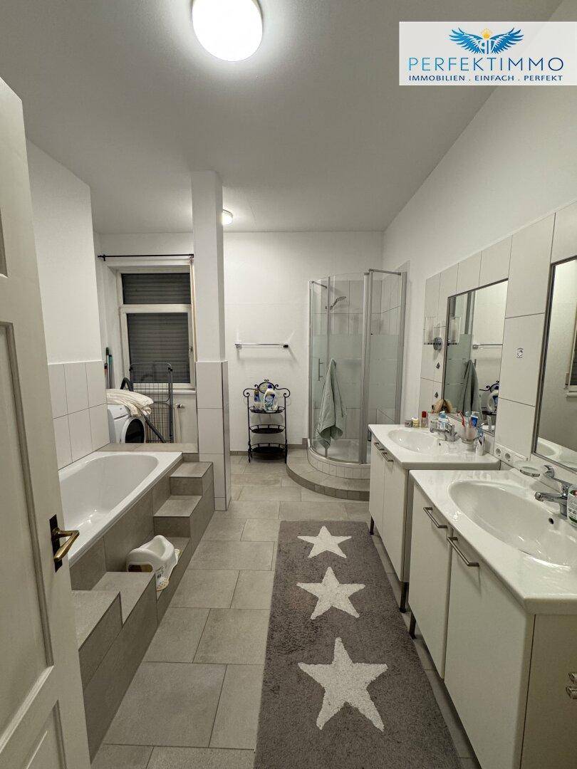 Geräumiges Badezimmer mit Badewanne, Duschkabine und Doppelwaschbecken.
