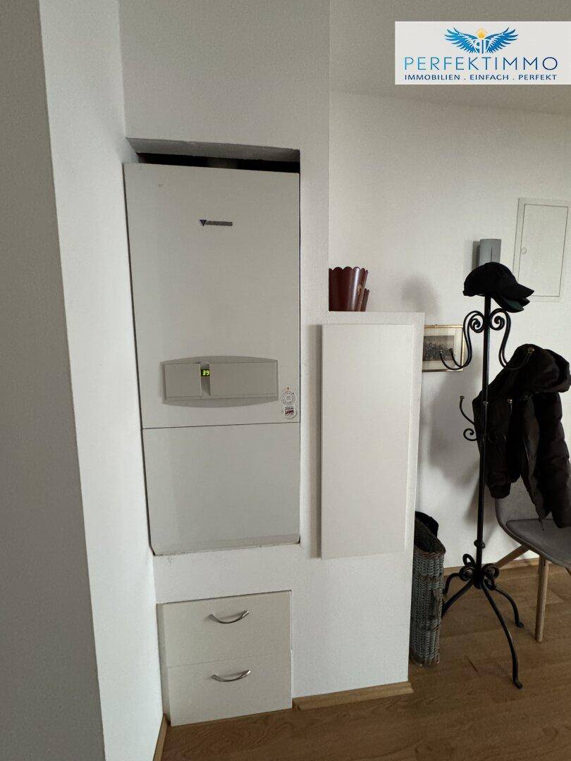 Flur mit wandmontierter Heizungsanlage und Garderobe.
