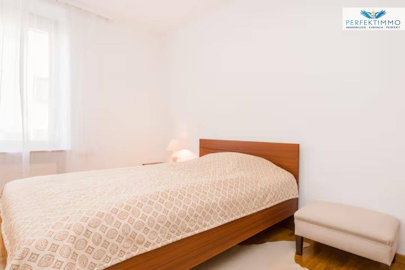 Schlafzimmer mit Einzelbett, Holzboden und einem Fenster, das viel Tageslicht spendet.