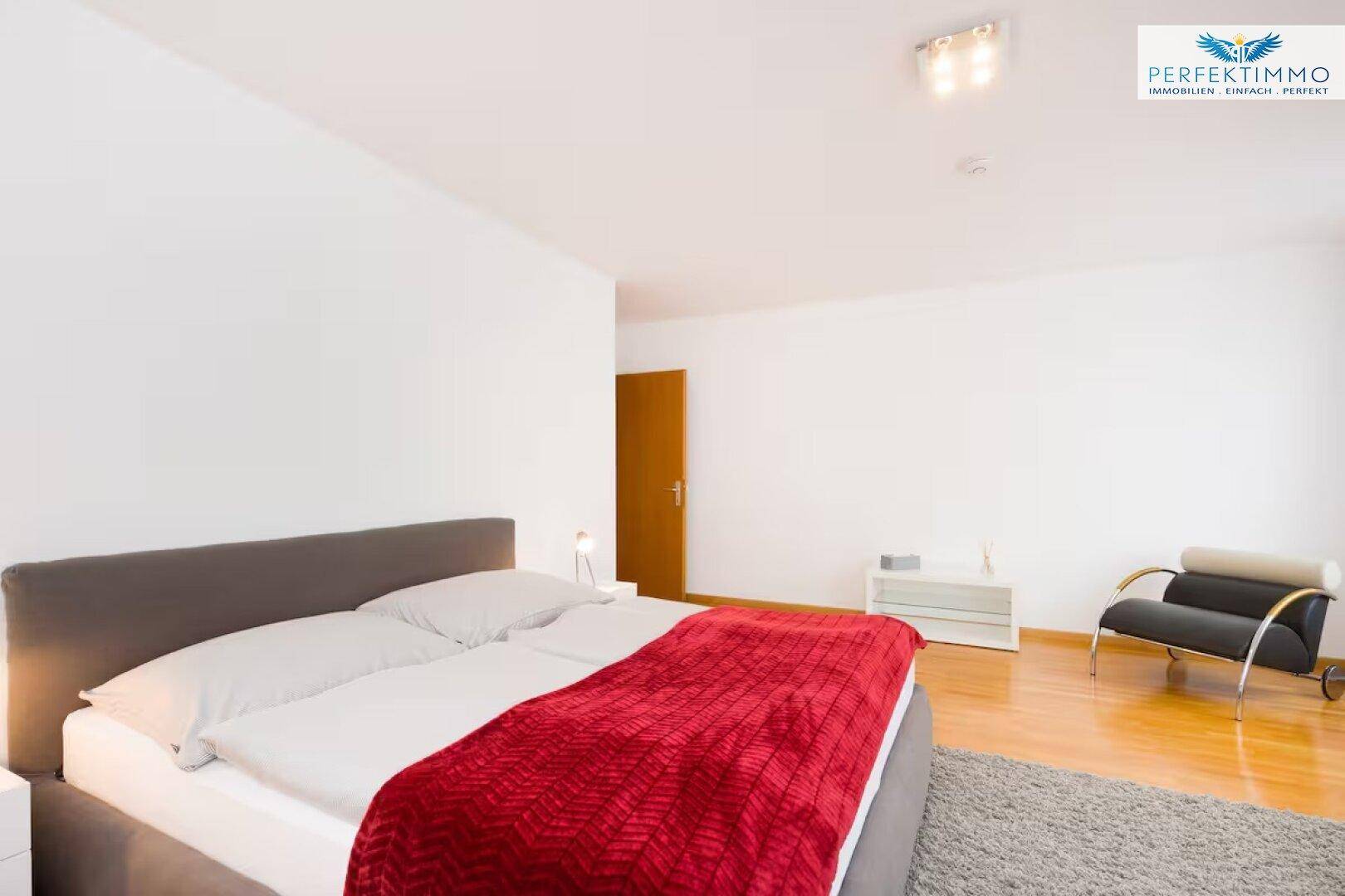Helles Schlafzimmer mit Holzboden, einem Doppelbett und minimalistischer Einrichtung.