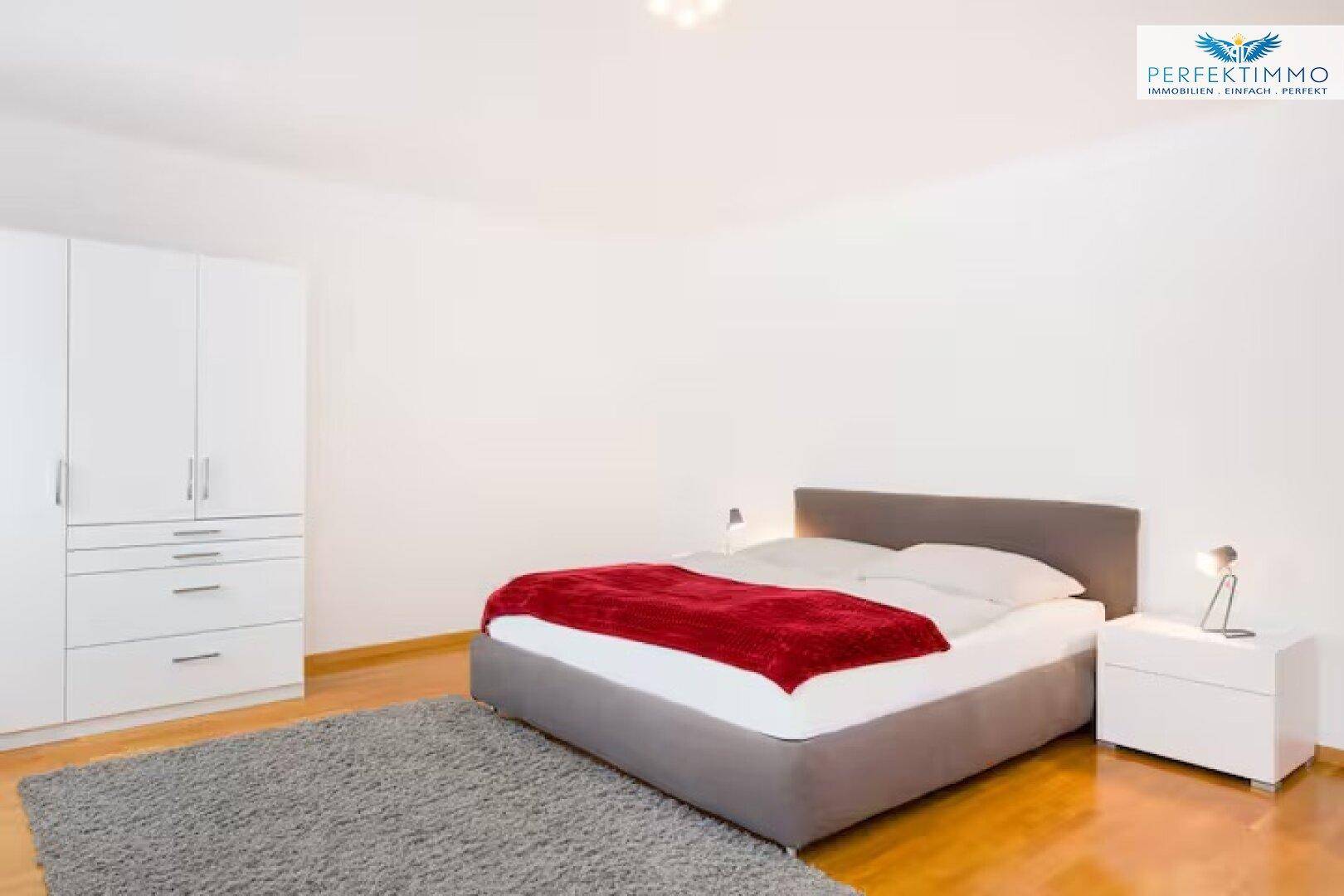 Geräumiges Schlafzimmer mit Holzboden, großem Bett und weißem Kleiderschrank.