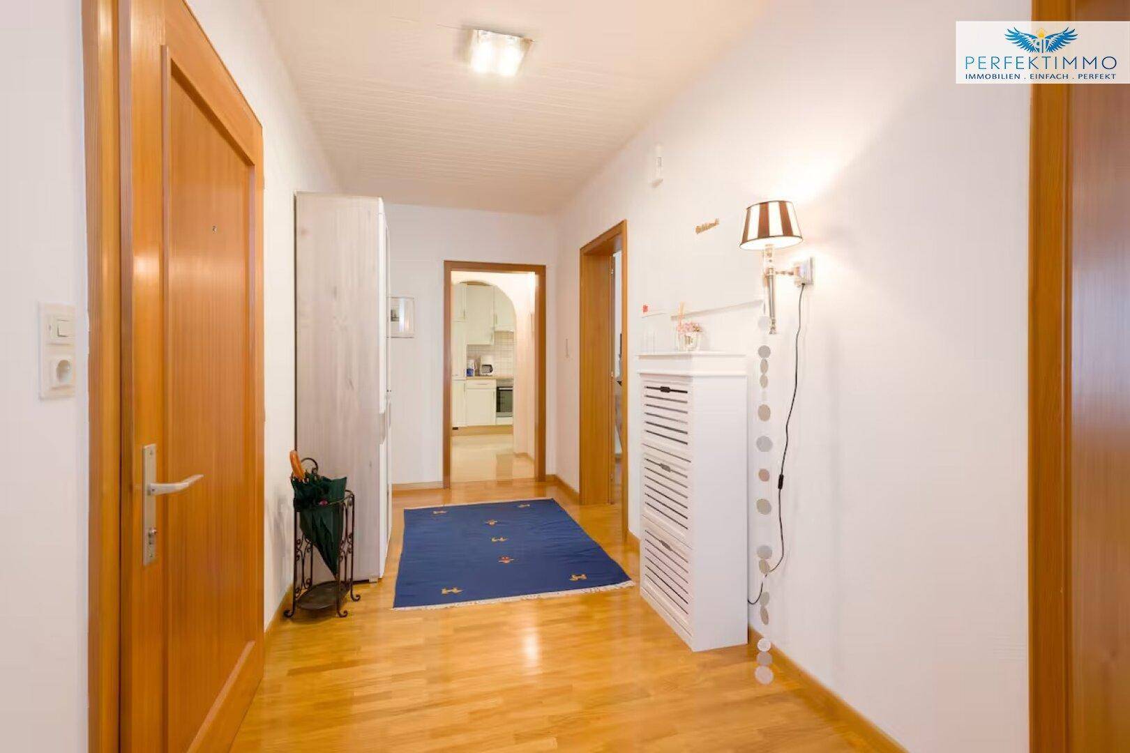 Heller Flur mit Holzboden, Garderobe und Zugang zu verschiedenen Räumen.