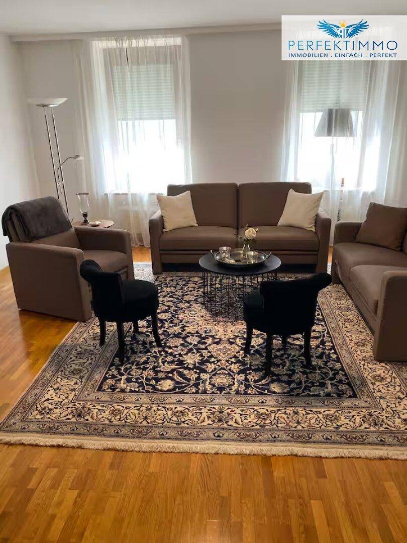 Gemütliches Wohnzimmer mit Holzboden, bequemen Sofas und einem orientalischen Teppich.