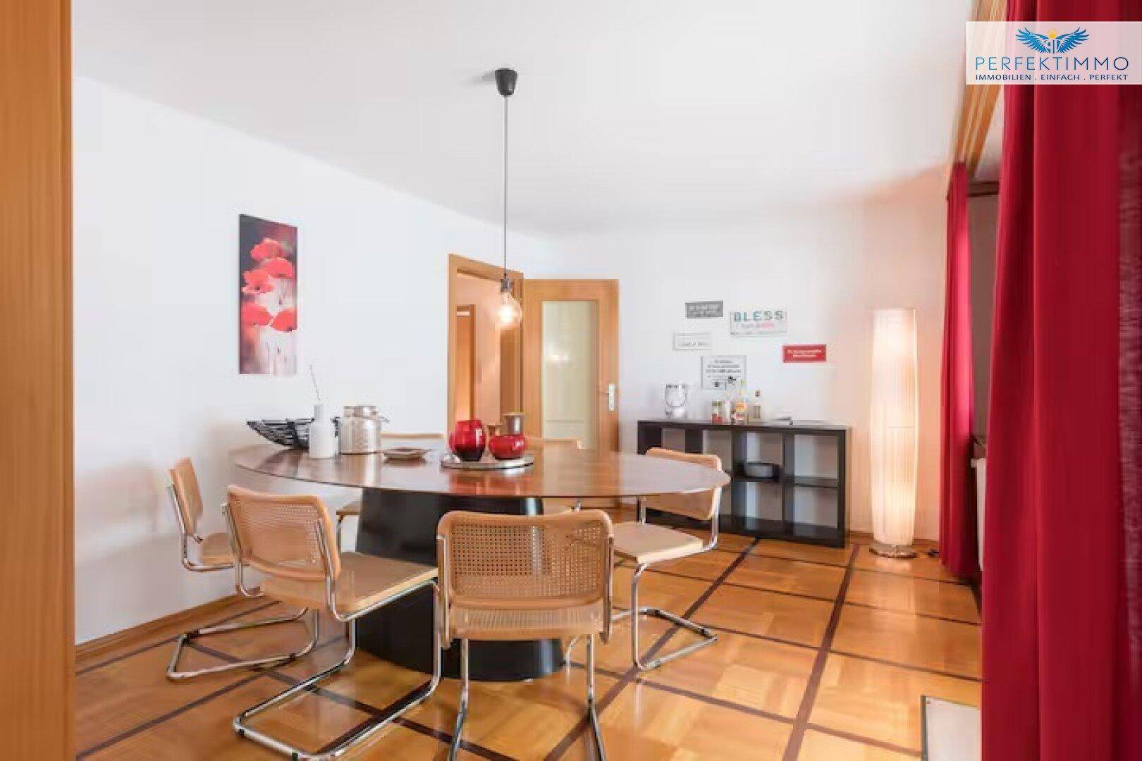 Esszimmer mit großem ovalen Holztisch, Korbstühlen und Parkettboden.