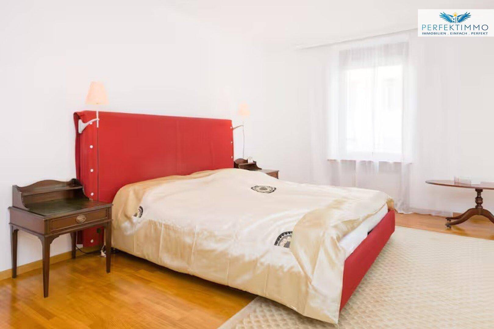 Helles Schlafzimmer mit Holzboden, großem Bett und antiken Nachttischen.