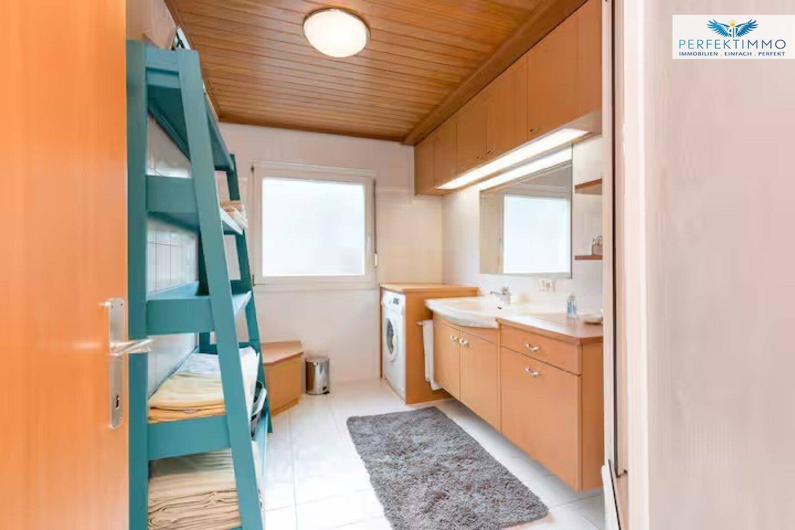 Badezimmer mit Etagenbett, Waschmaschine, Waschbecken und Holzdecke.
