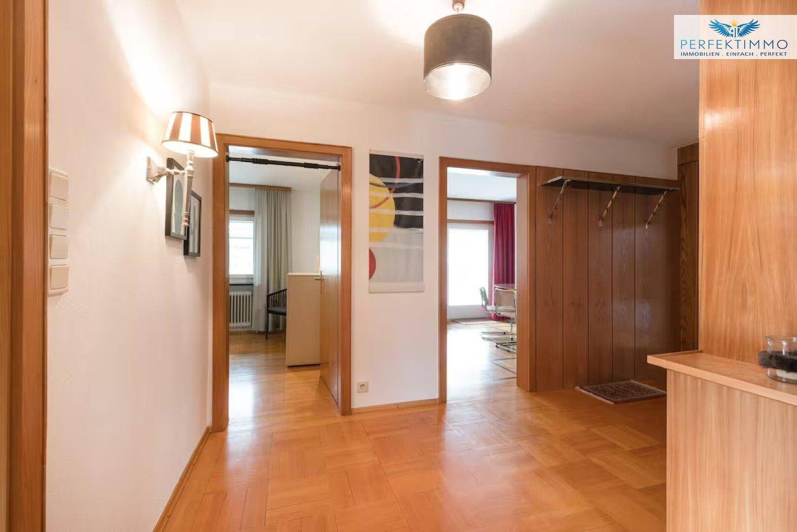 Heller Flur mit Holzboden und Zugang zu verschiedenen Zimmern.
