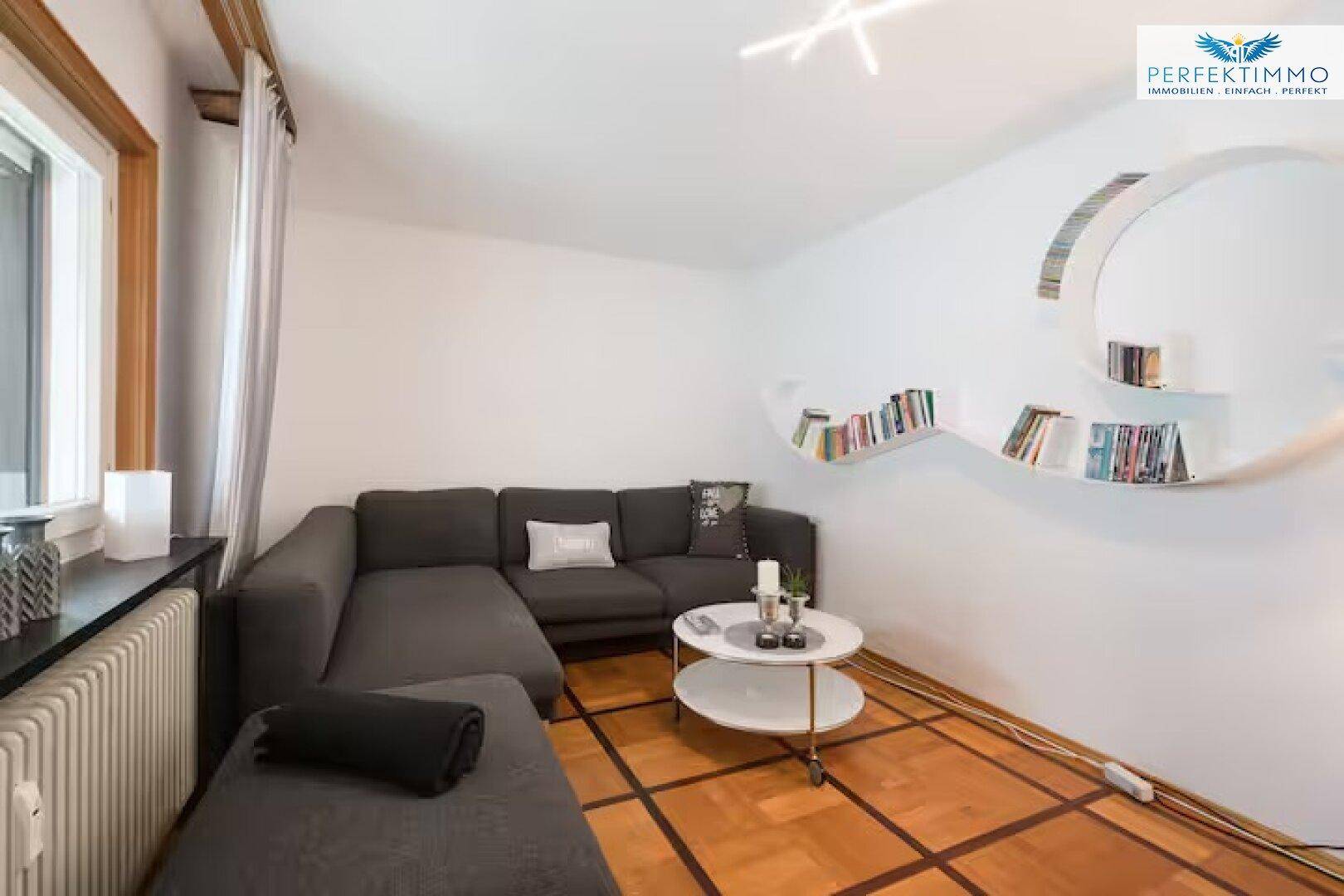 Modernes Wohnzimmer mit grauem Ecksofa, Couchtisch und Parkettboden.